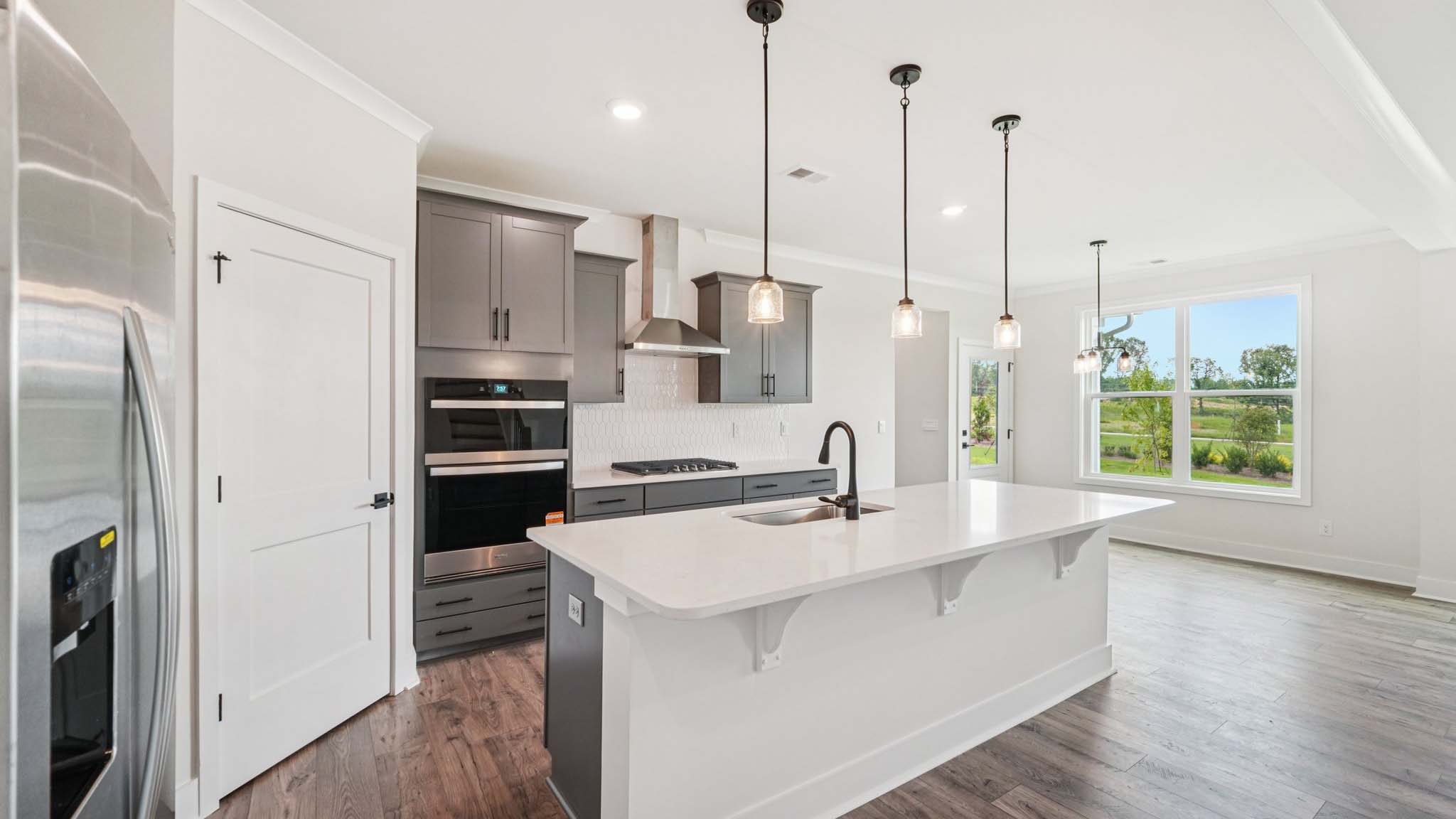 Open concept kitchen with gray cabinets, white countertops and stainless steel appliances