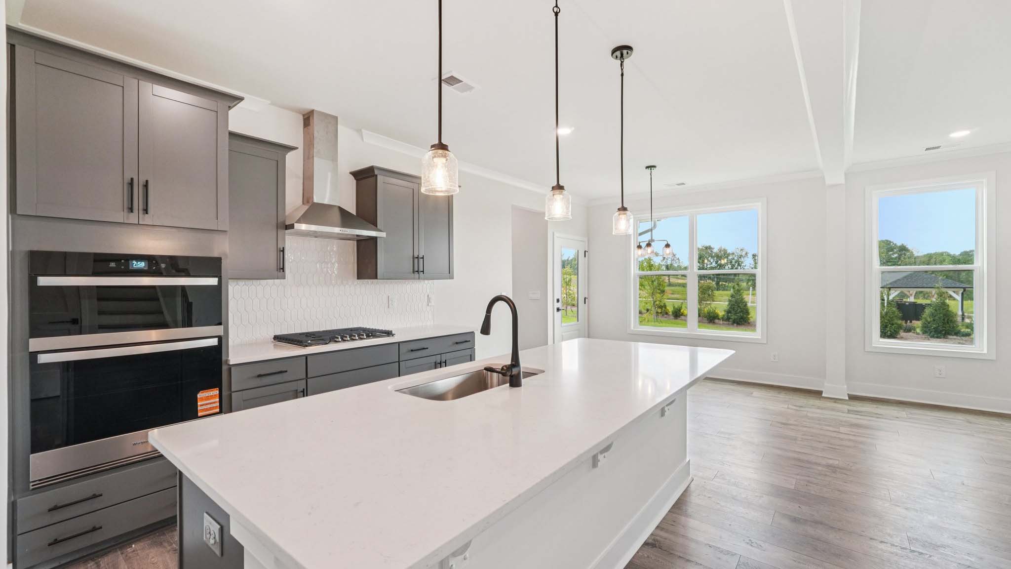 Open concept kitchen with gray cabinets, white countertops and stainless steel appliances