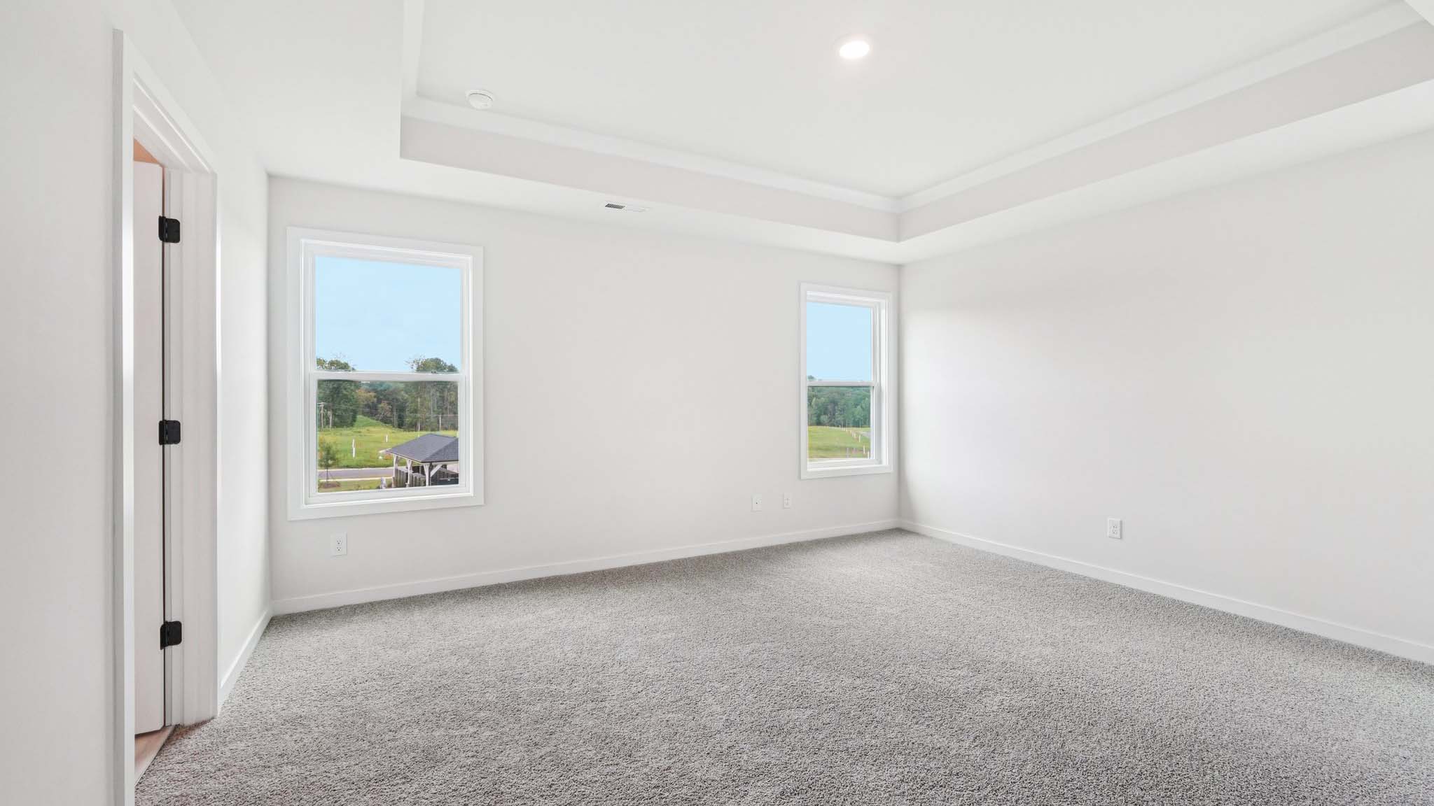 Primary carpeted bedroom with large windows