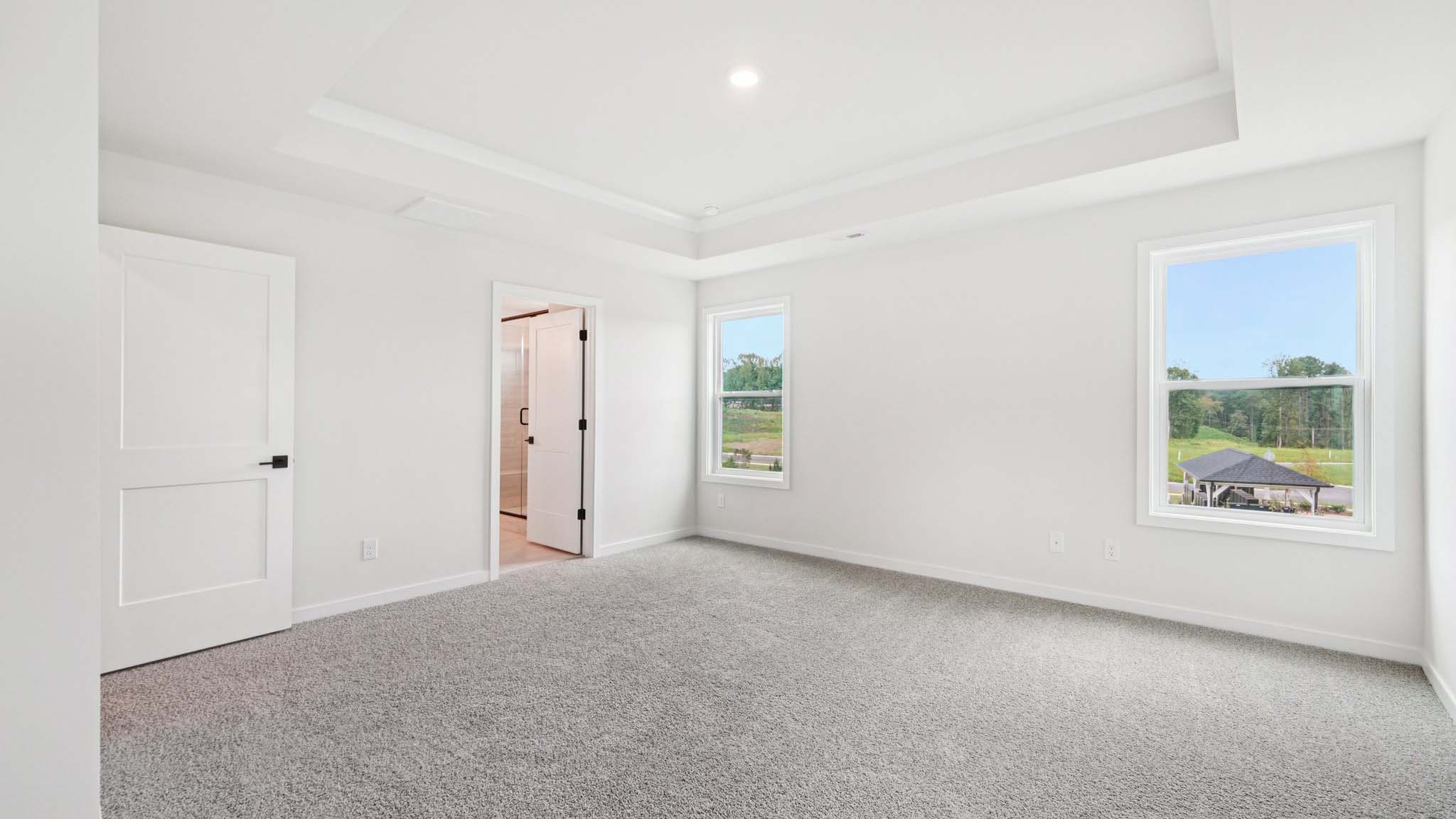 Primary carpeted bedroom with large windows