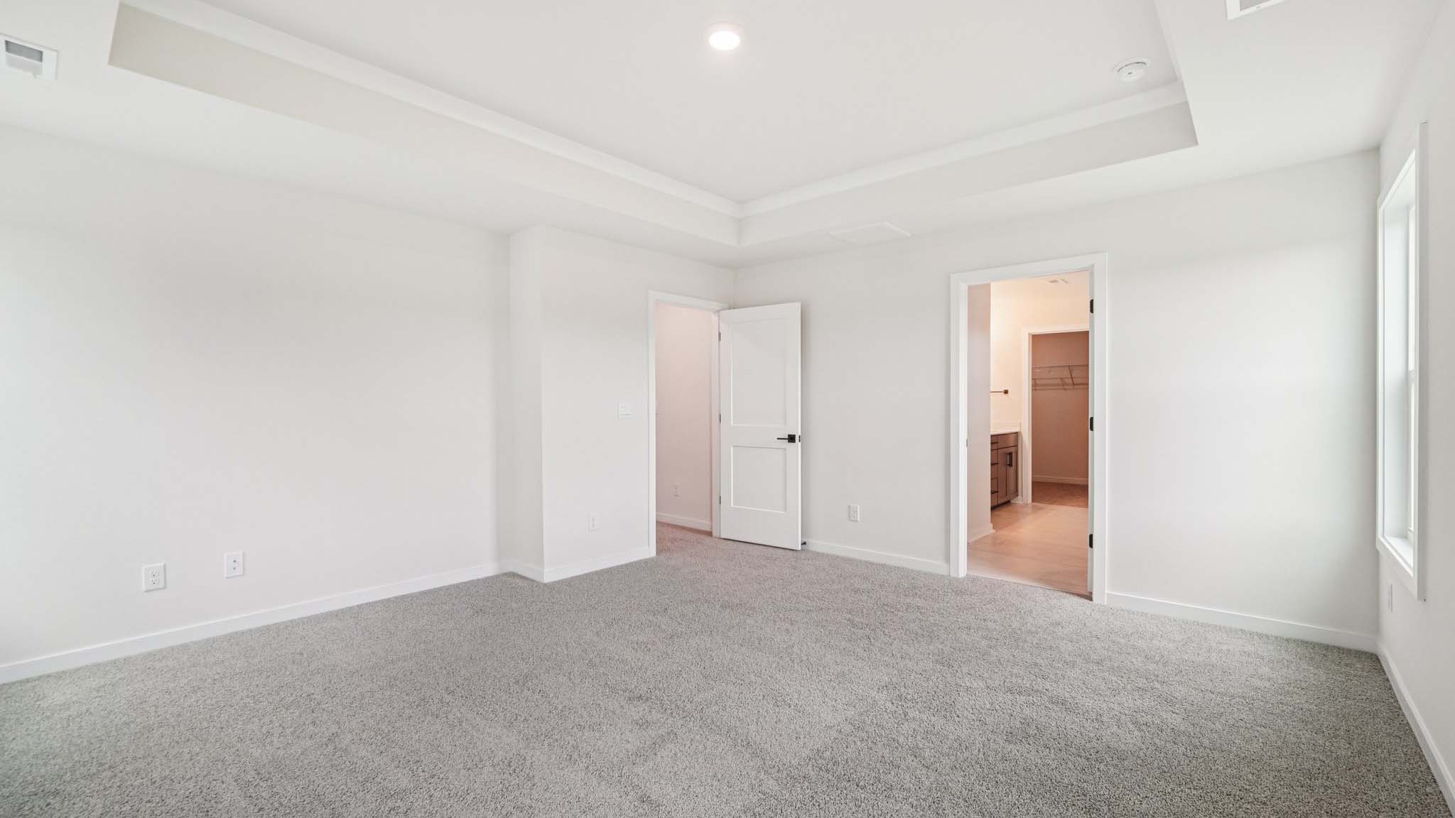 Primary carpeted bedroom with large windows