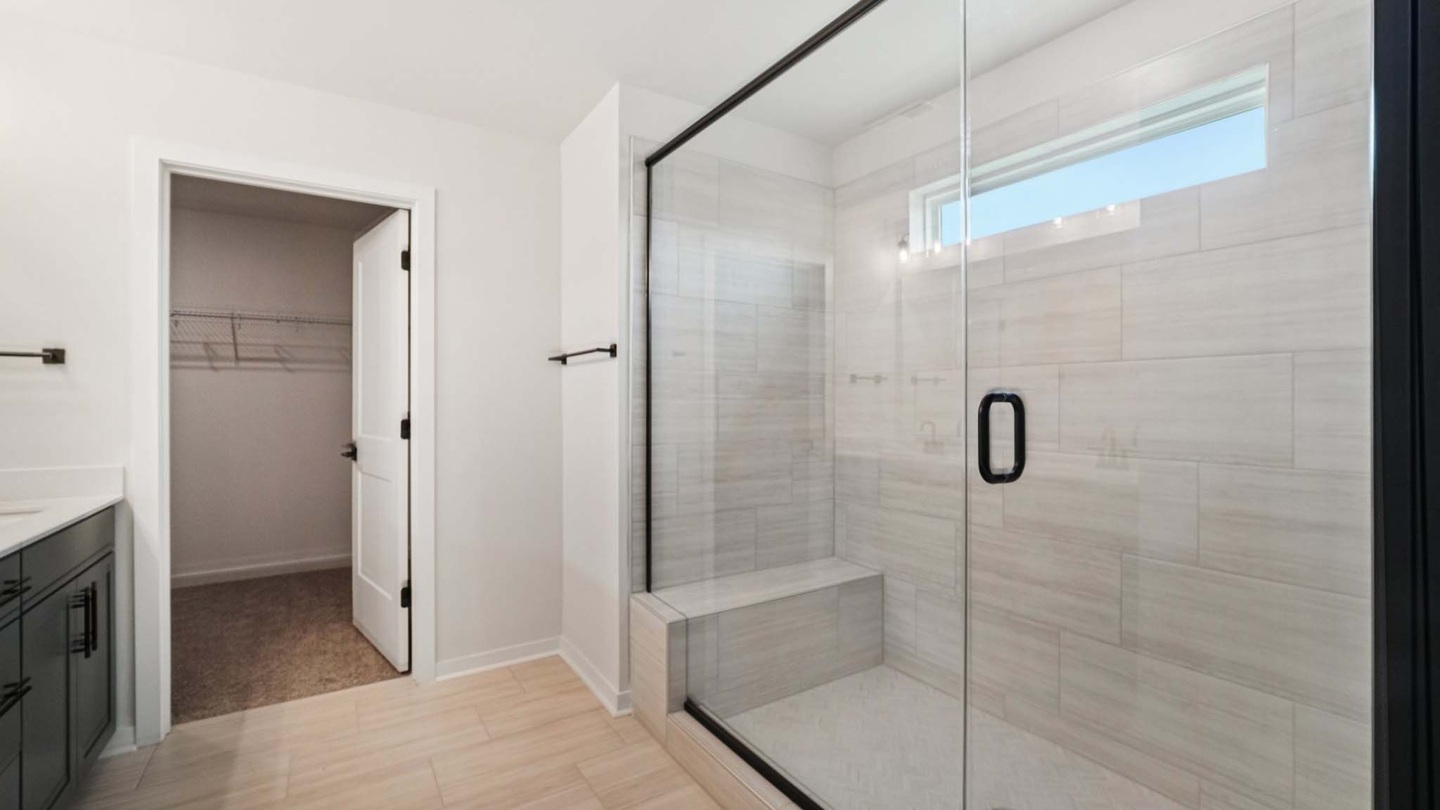 primary bathroom with double sinks, glass door shower, and bathtub