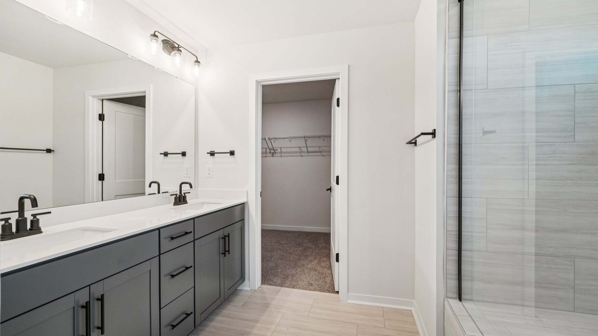 primary bathroom with double sinks, glass door shower, and bathtub