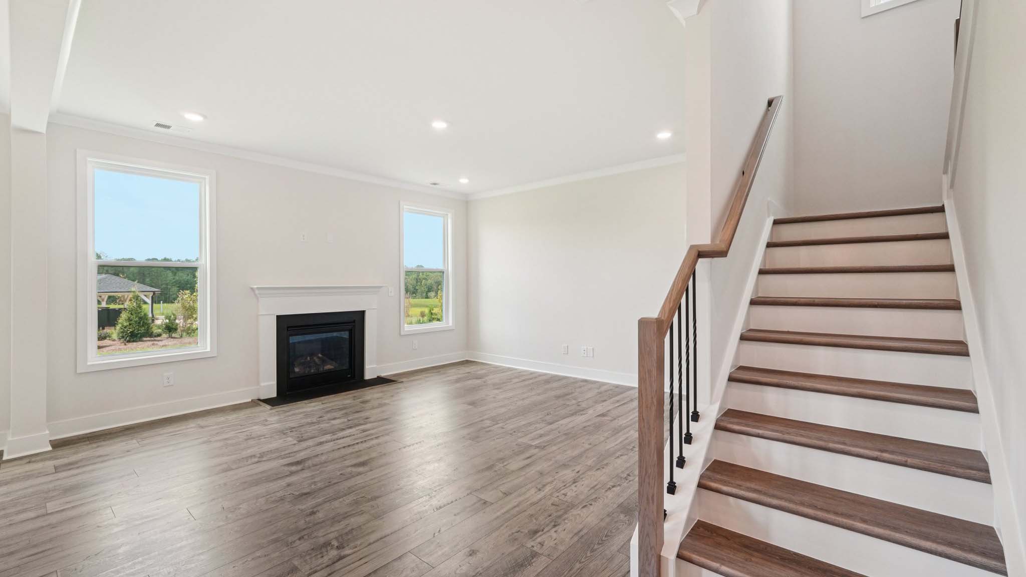 Open concept family room with two large windows and a fireplace