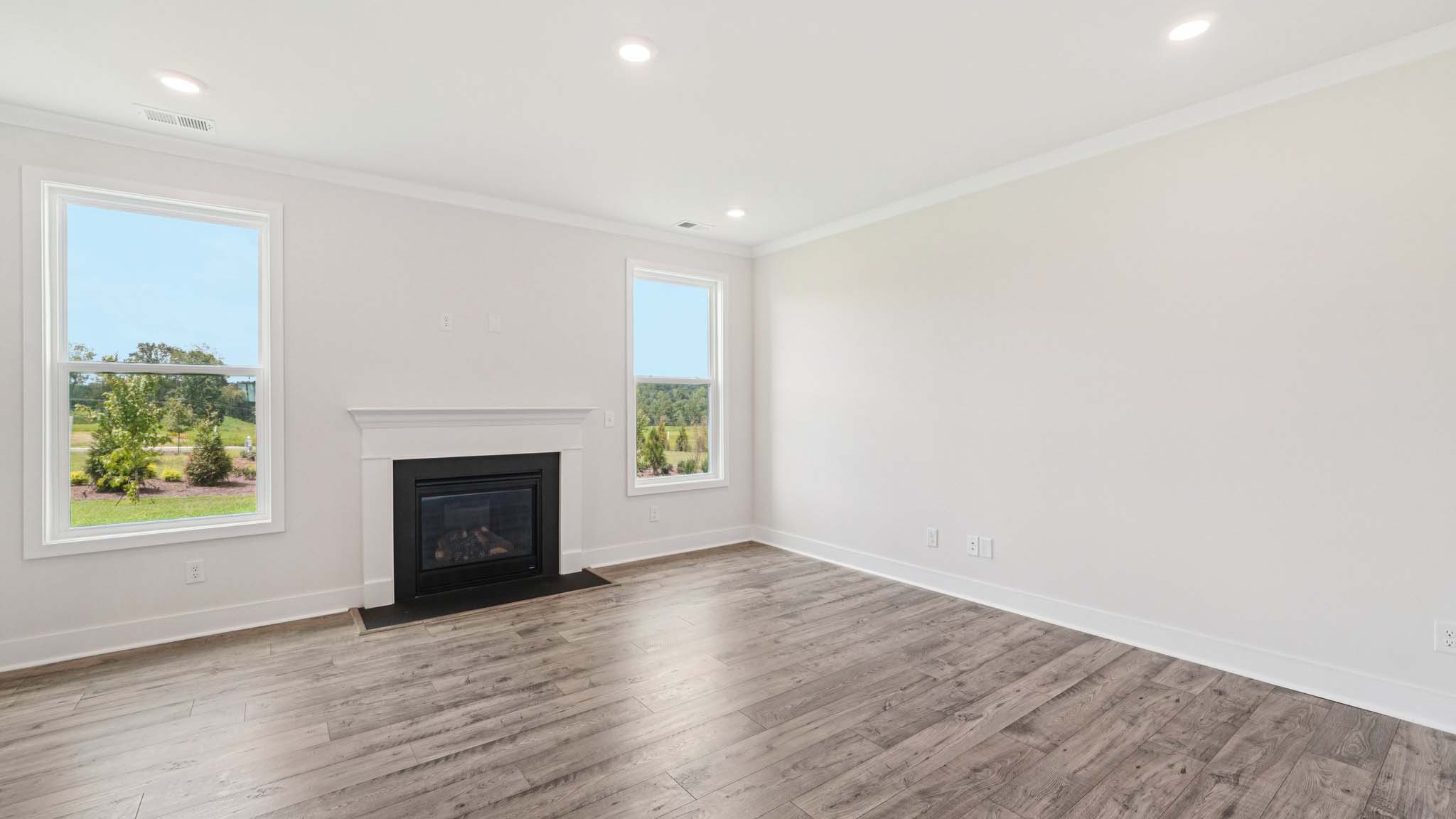 Open concept family room with two large windows and a fireplace