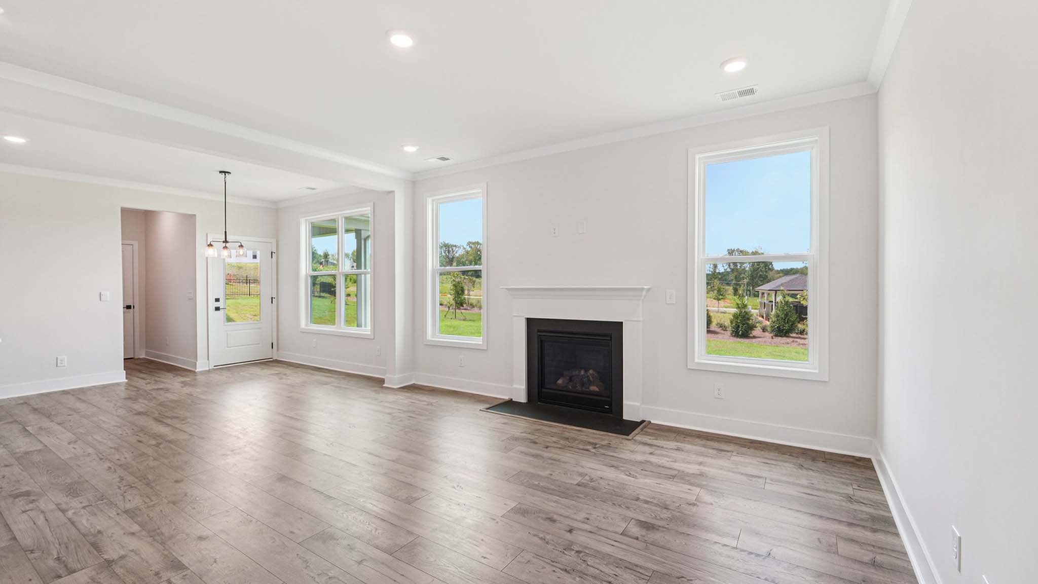 Open concept family room with two large windows and a fireplace