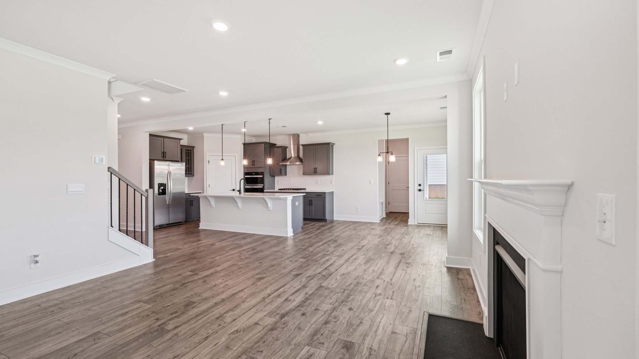 Open concept family room with two large windows and a fireplace