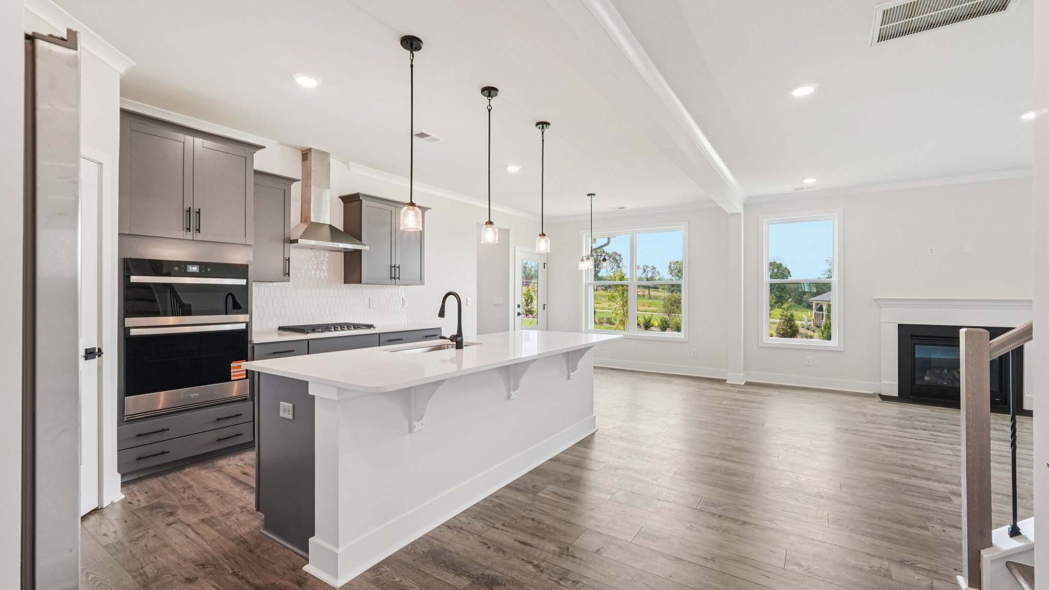 Open concept kitchen with gray cabinets, white countertops and stainless steel appliances