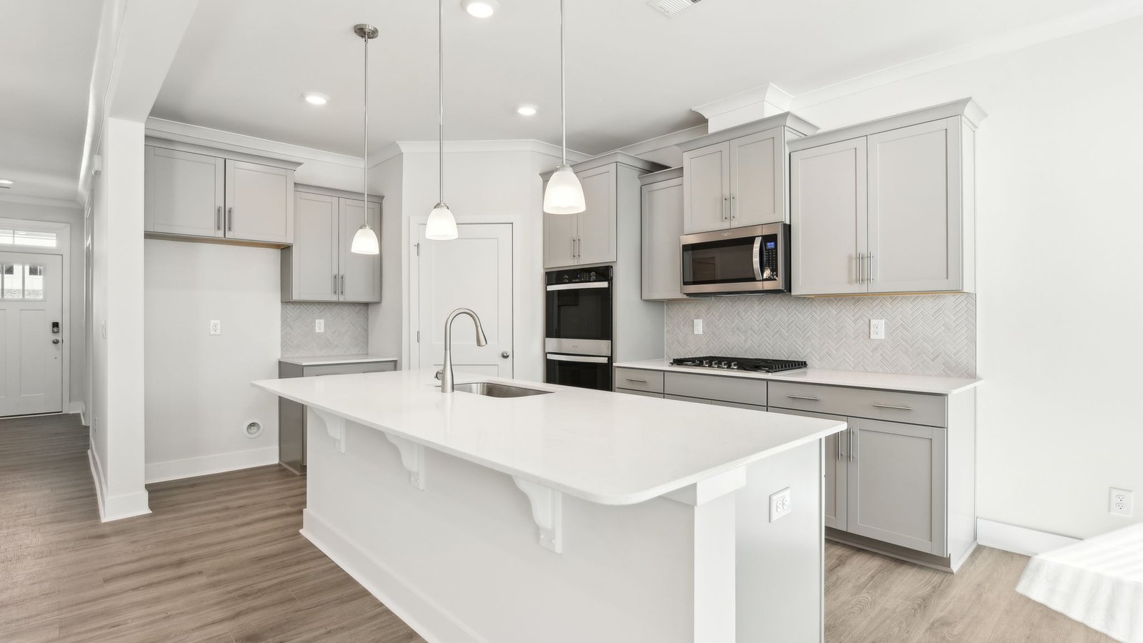 Open concept kitchen with gray cabinets, white countertops and stainless steel appliances