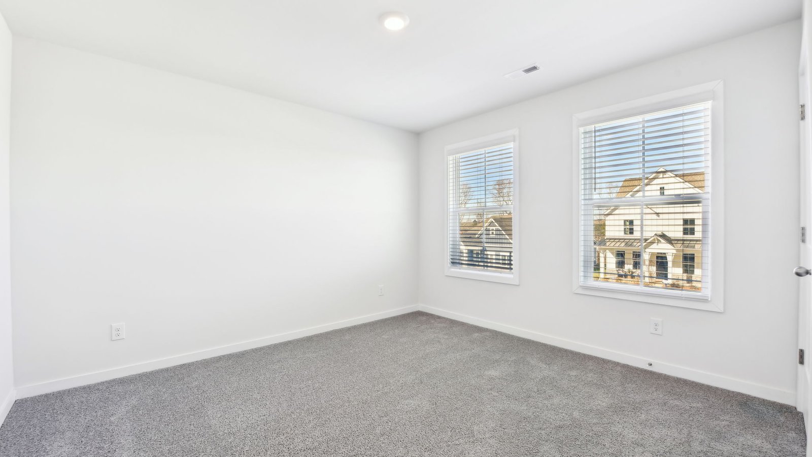 carpeted bedroom with two large windows