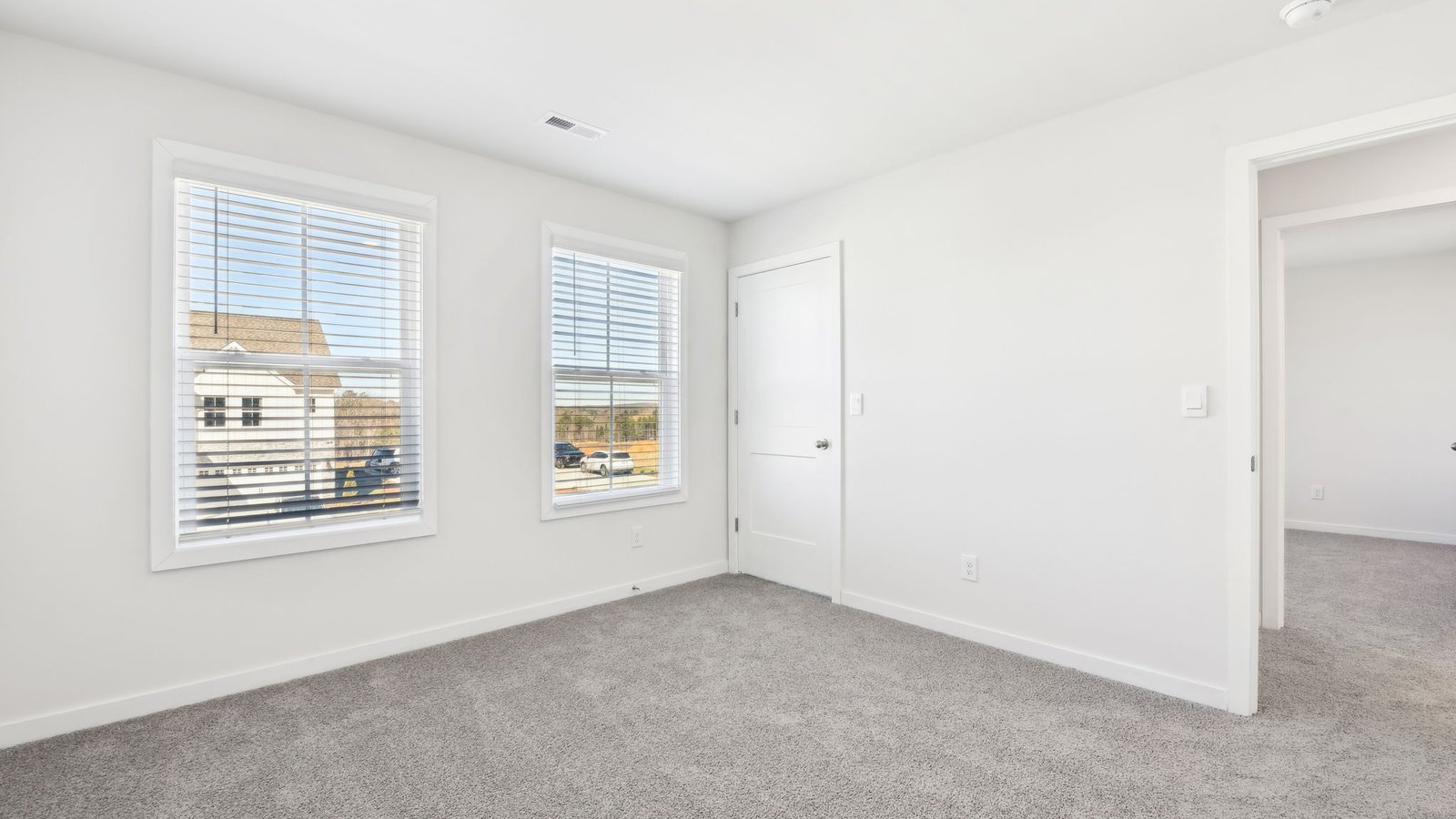 carpeted bedroom with two large windows