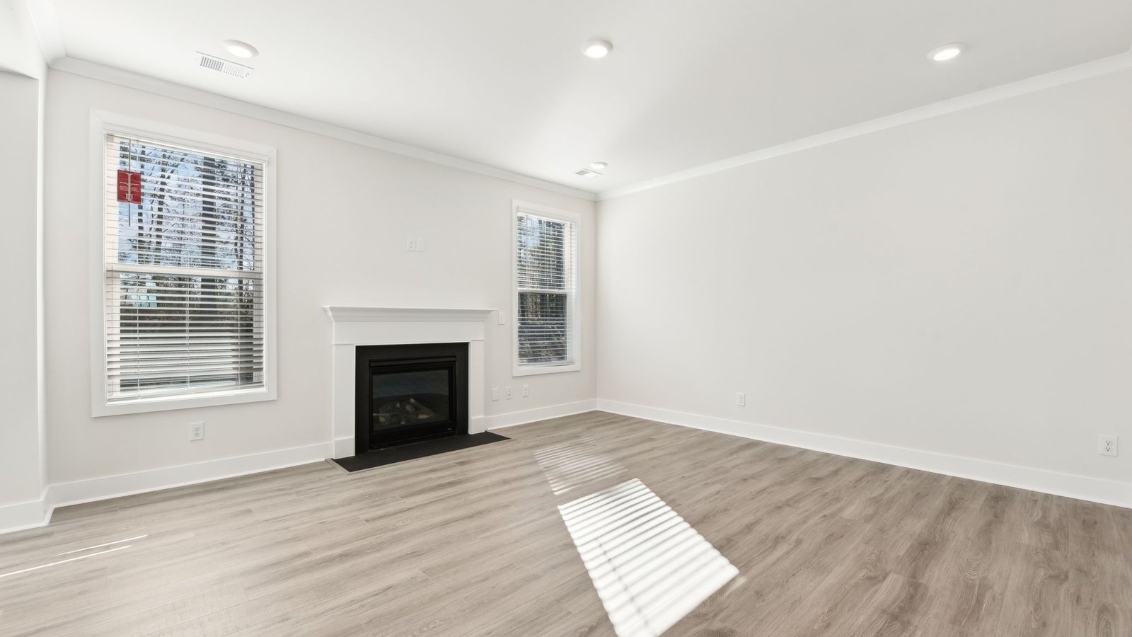 Open concept family room with two large windows and a fireplace
