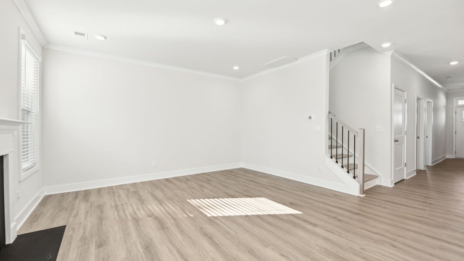 Open concept family room with two large windows and a fireplace