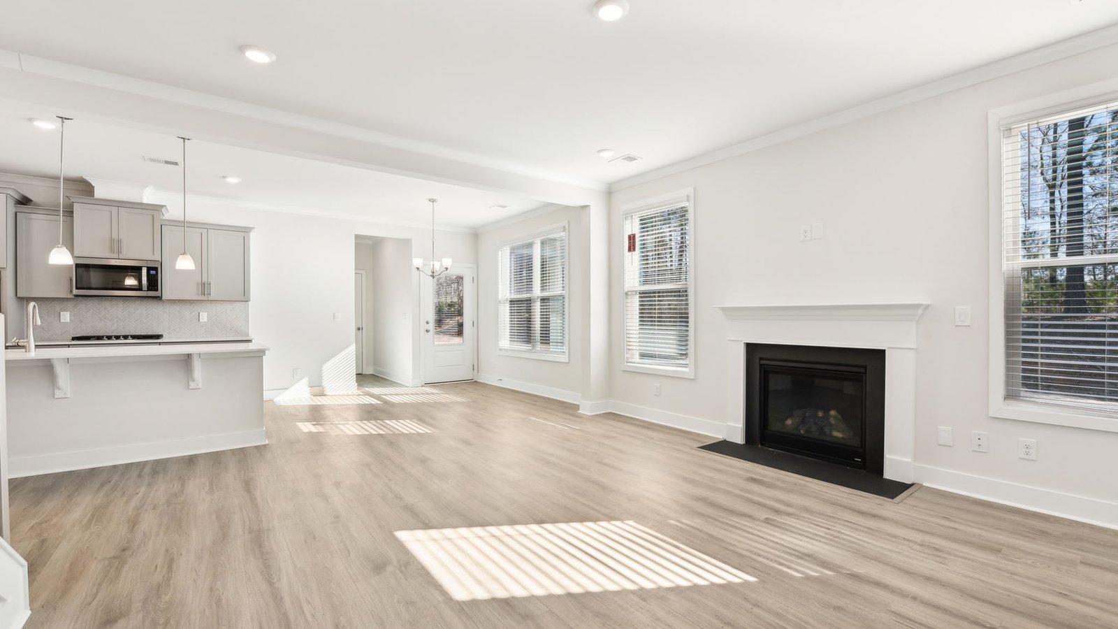Open concept family room with two large windows and a fireplace