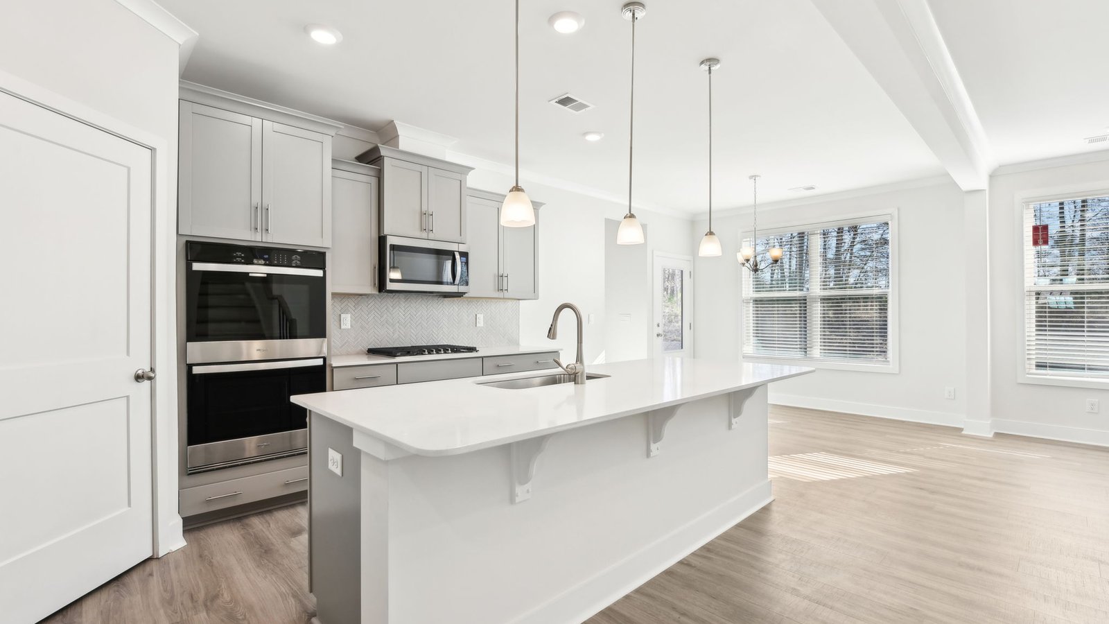 Open concept kitchen with gray cabinets, white countertops and stainless steel appliances