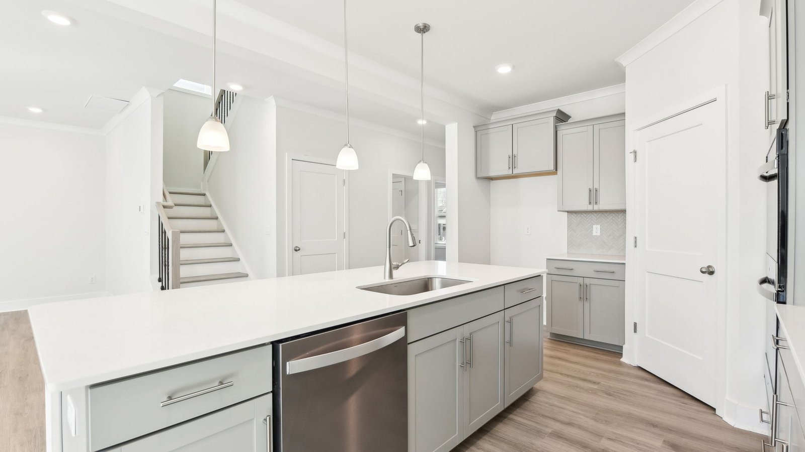 Open concept kitchen with gray cabinets, white countertops and stainless steel appliances