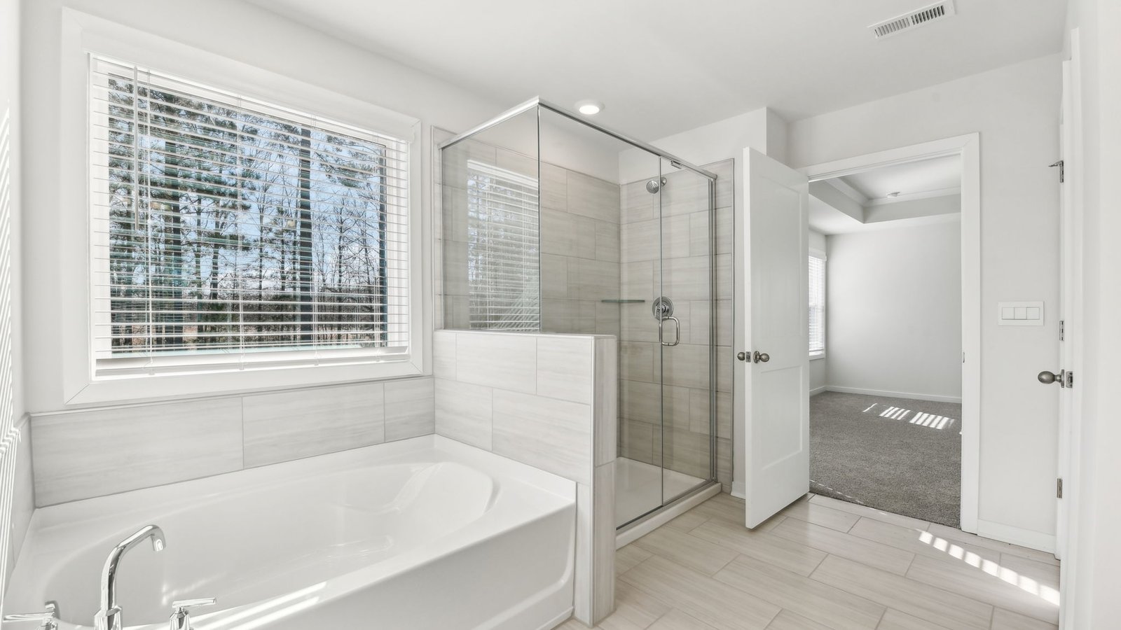primary bathroom with double sinks, glass door shower, and bathtub