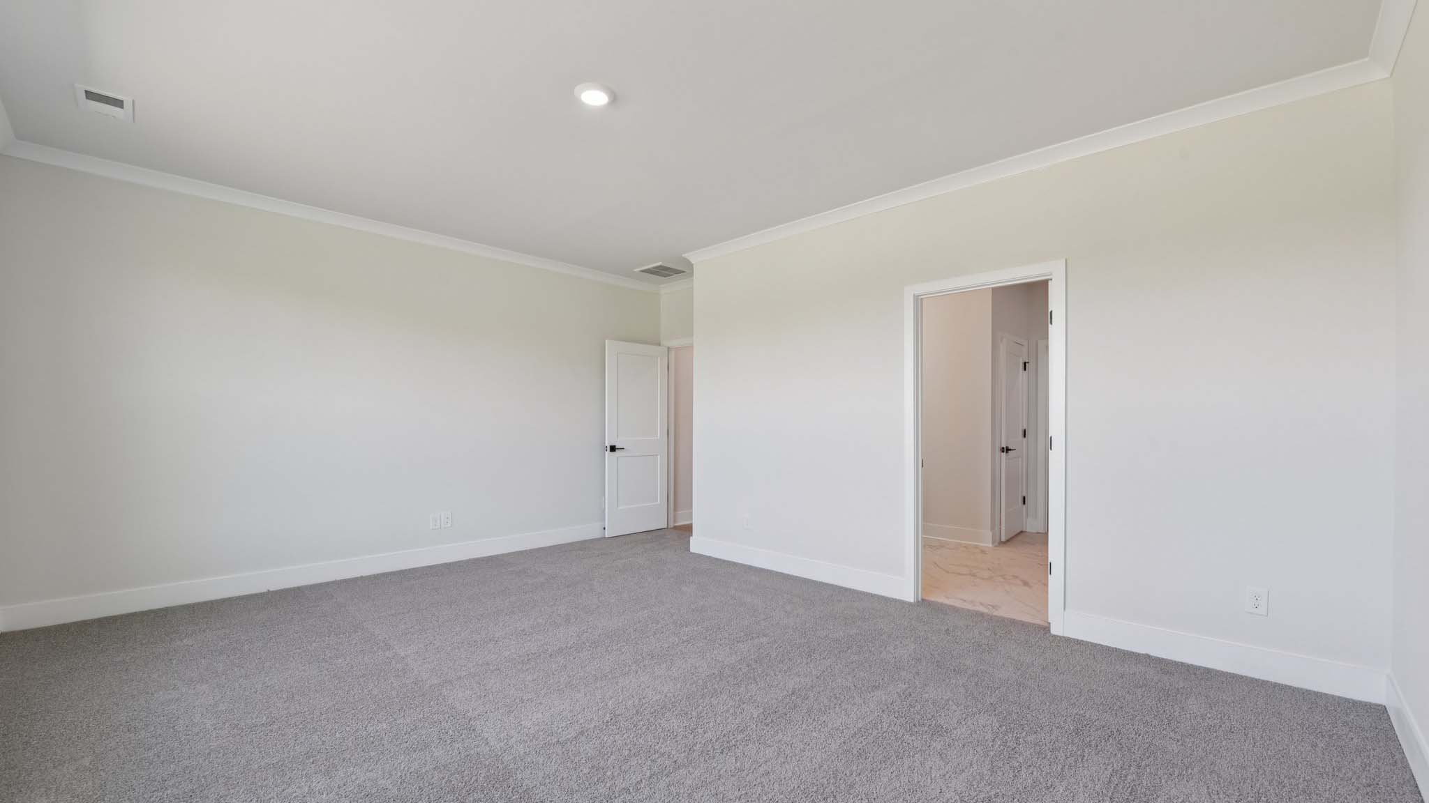 Primary carpeted bedroom with large windows