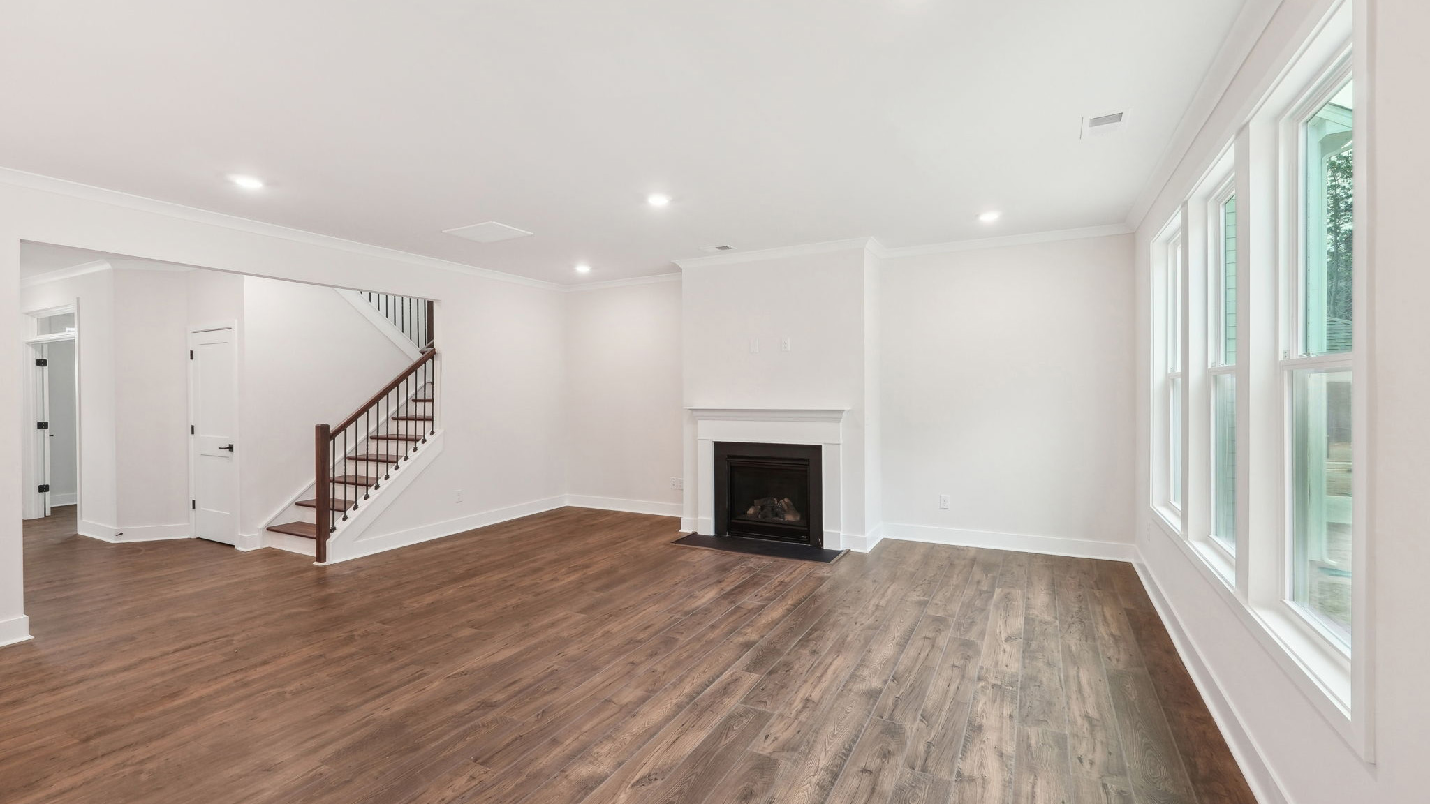 open concept living area with 3 large windows and fireplace
