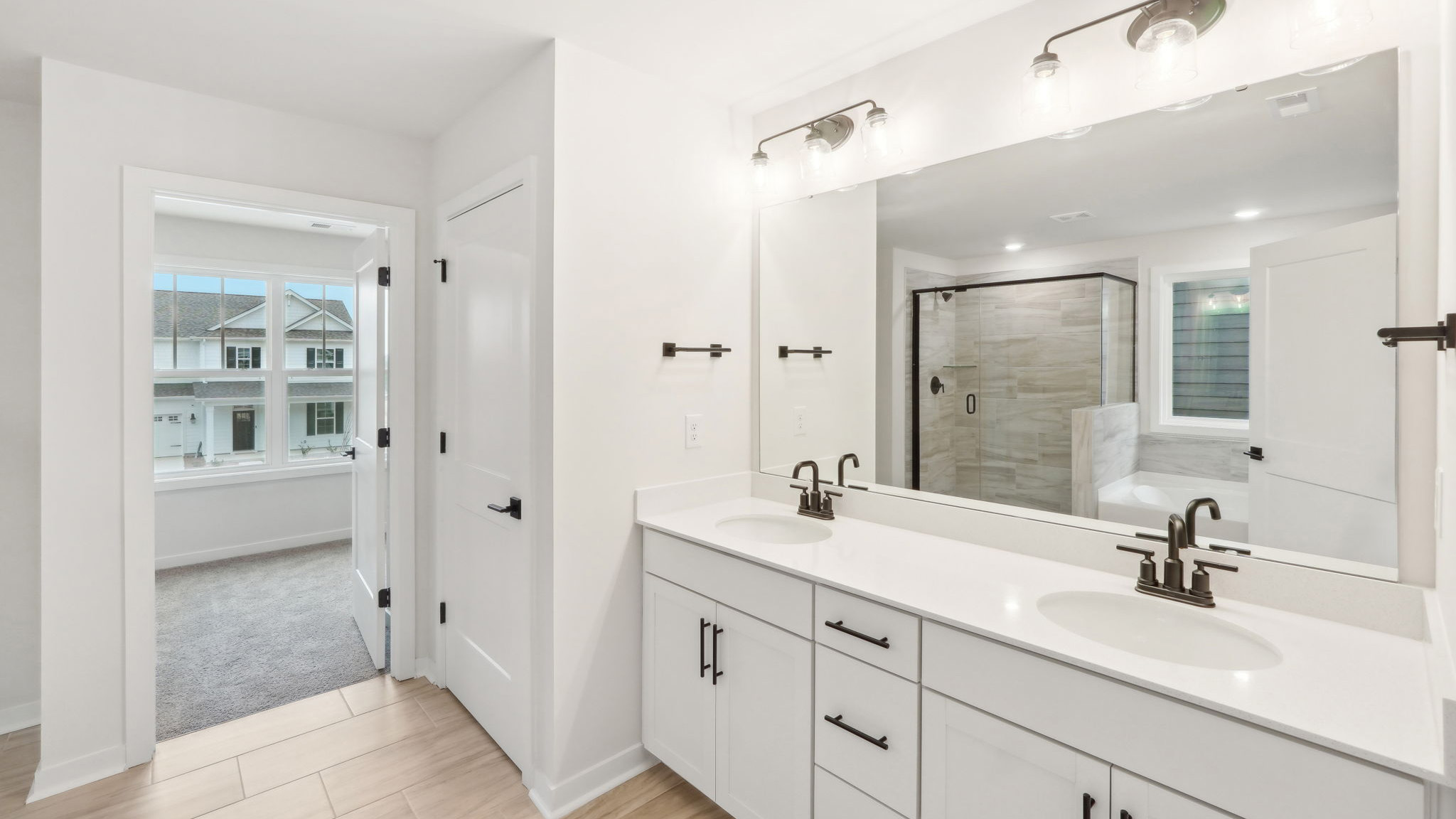 primary bathroom with dual vanity, bathtub and glass door shower