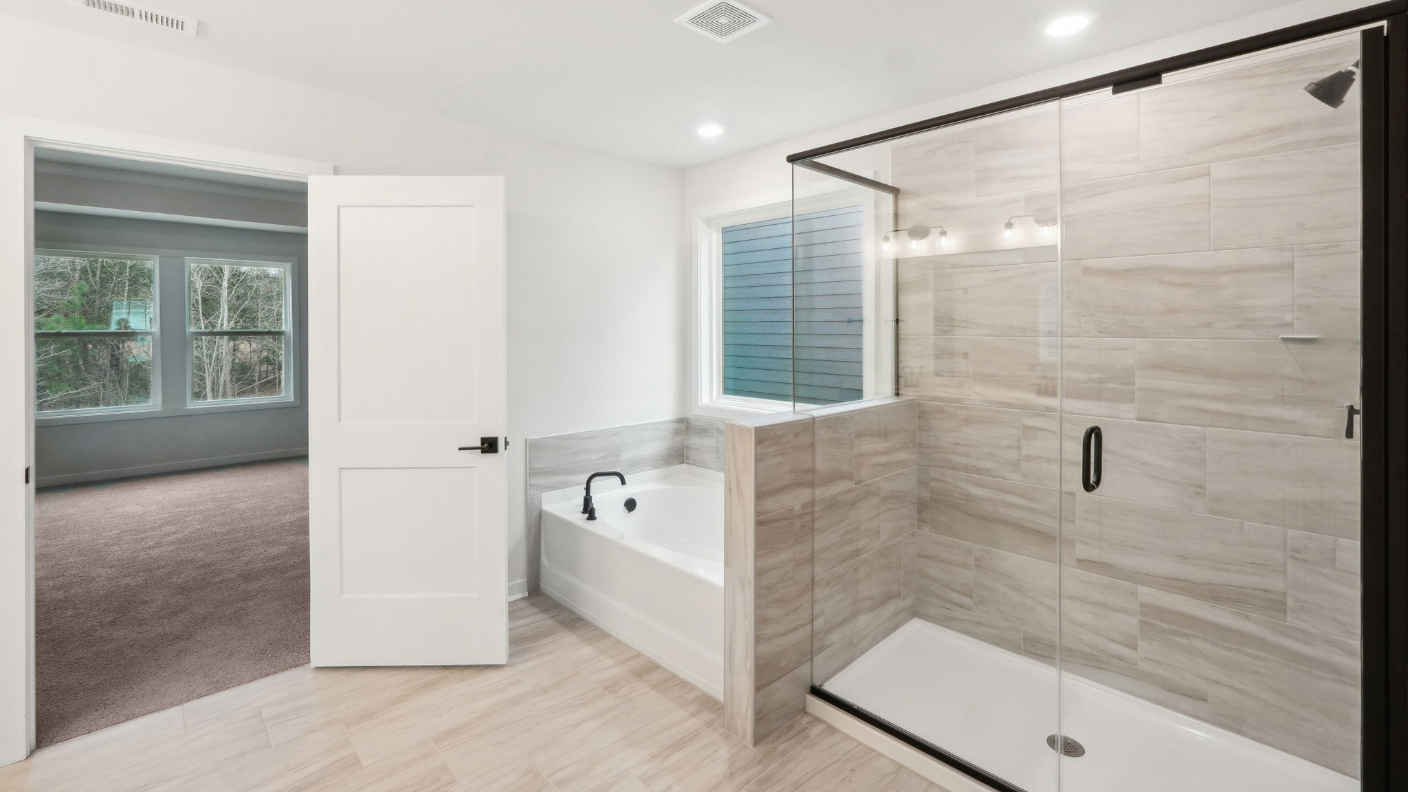 primary bathroom with dual vanity, bathtub and glass door shower