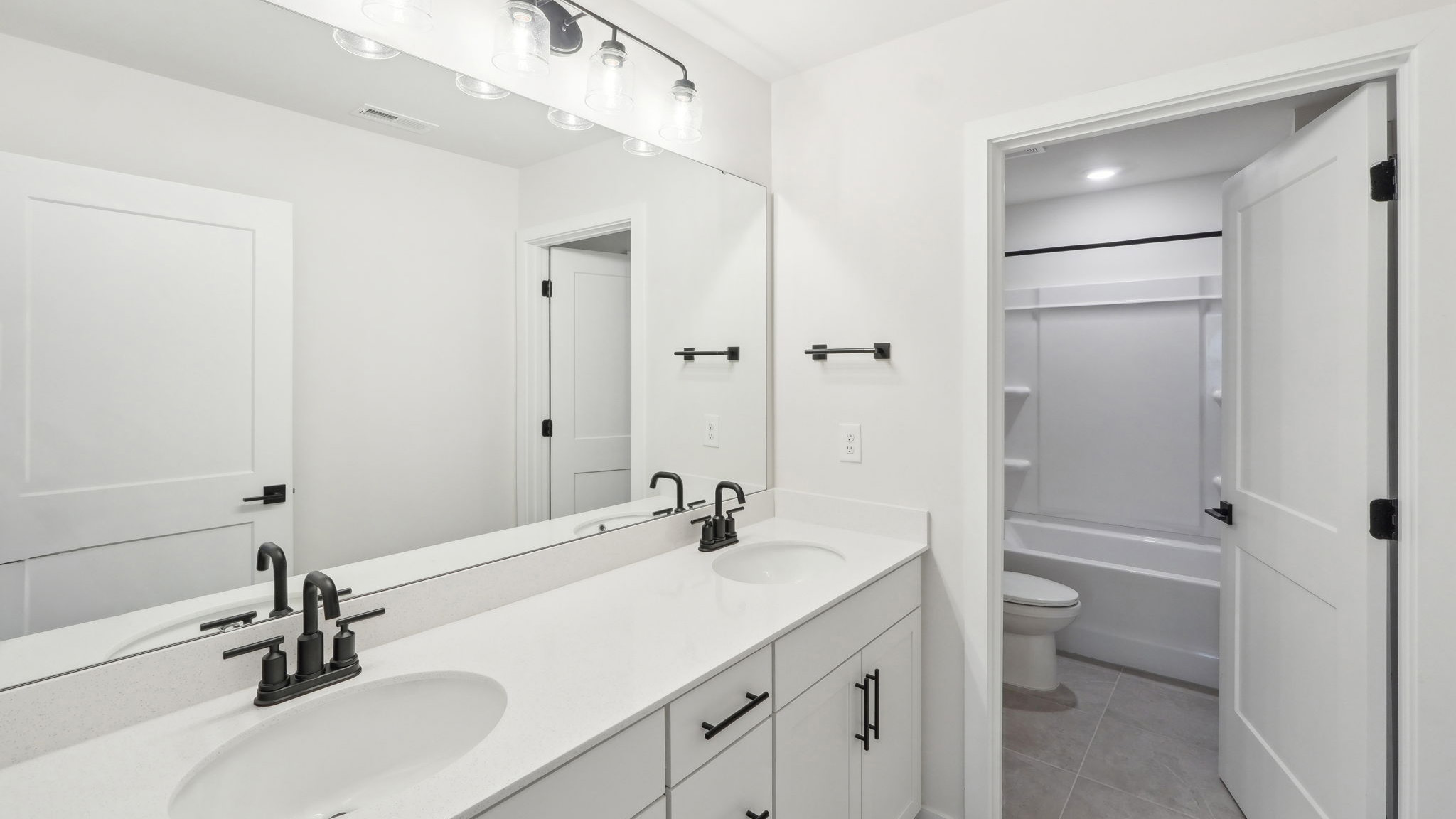 bathroom with double sinks and separate room for toilet and bathtub and shower combination