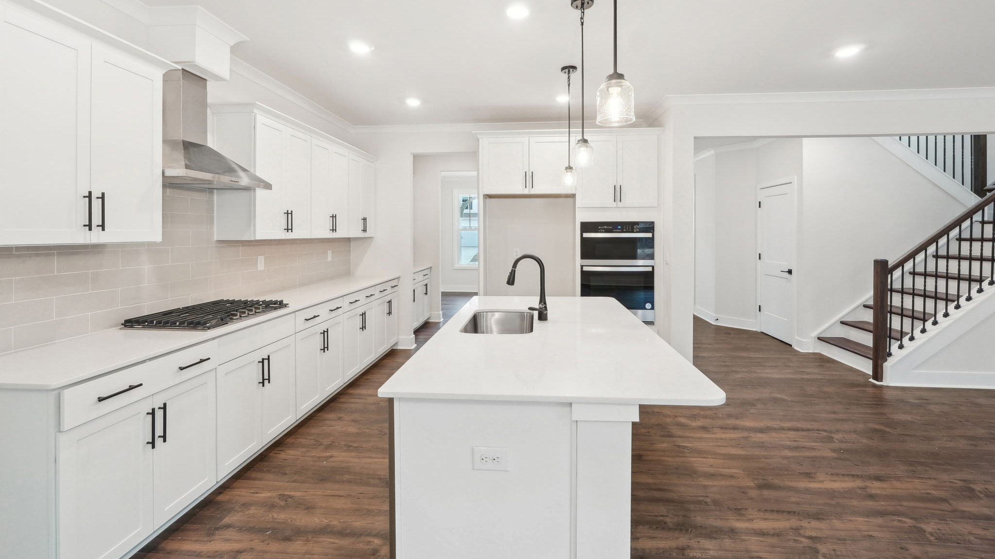 open concept kitchen with large island, white cabinets and countertops and stainless steel appliances
