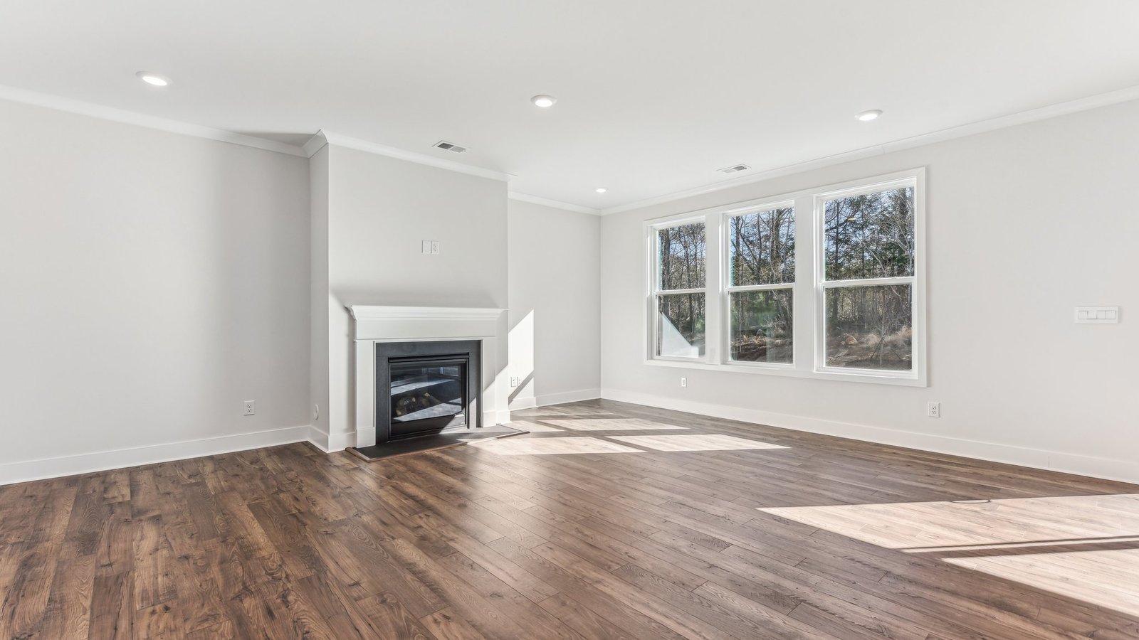 open concept living area with 3 large windows and fireplace