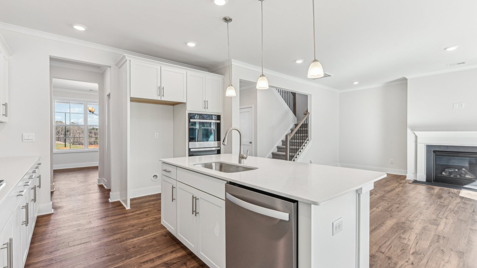 open concept kitchen with large island, white cabinets and countertops and stainless steel appliances