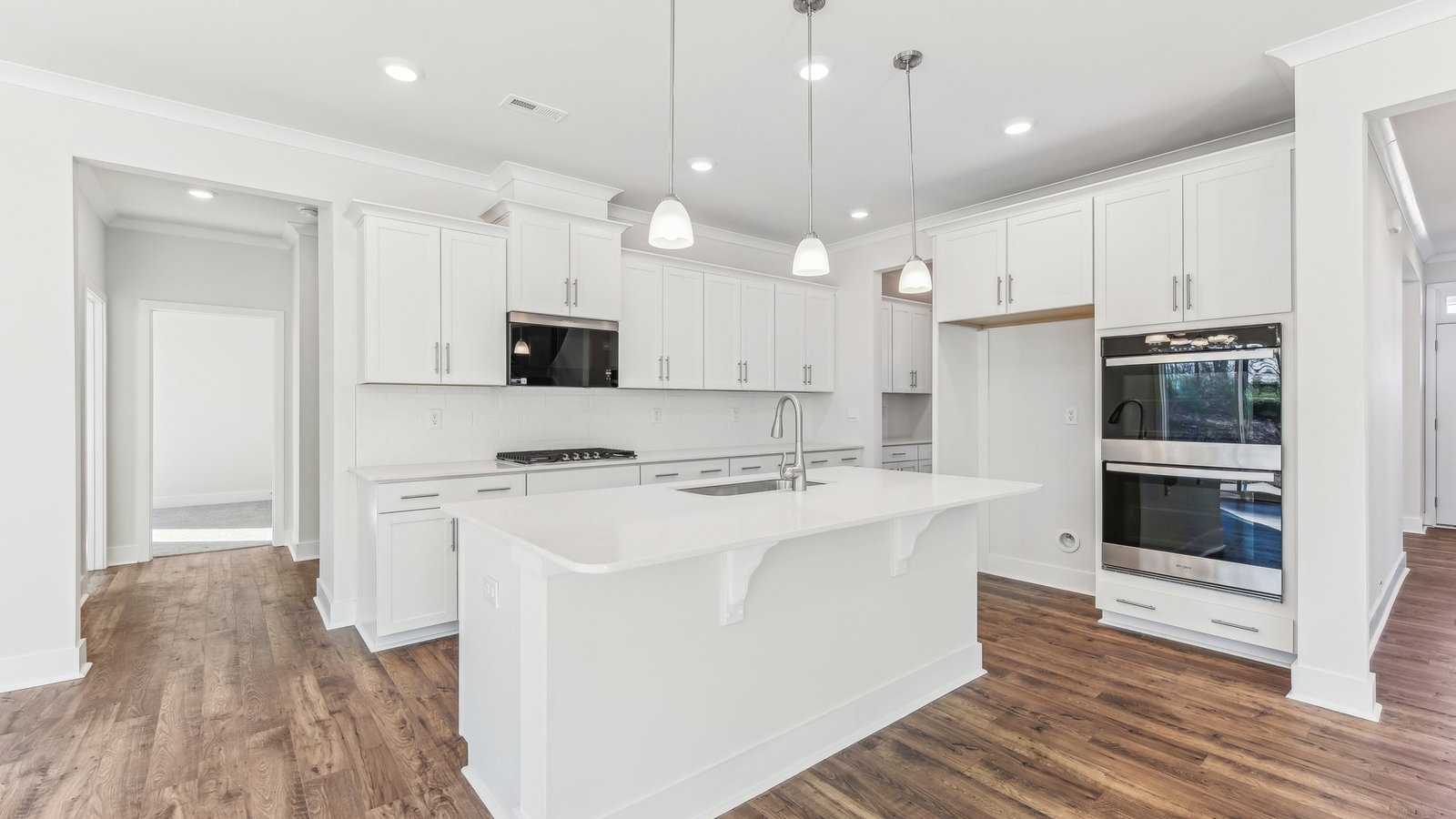 open concept kitchen with large island, white cabinets and countertops and stainless steel appliances