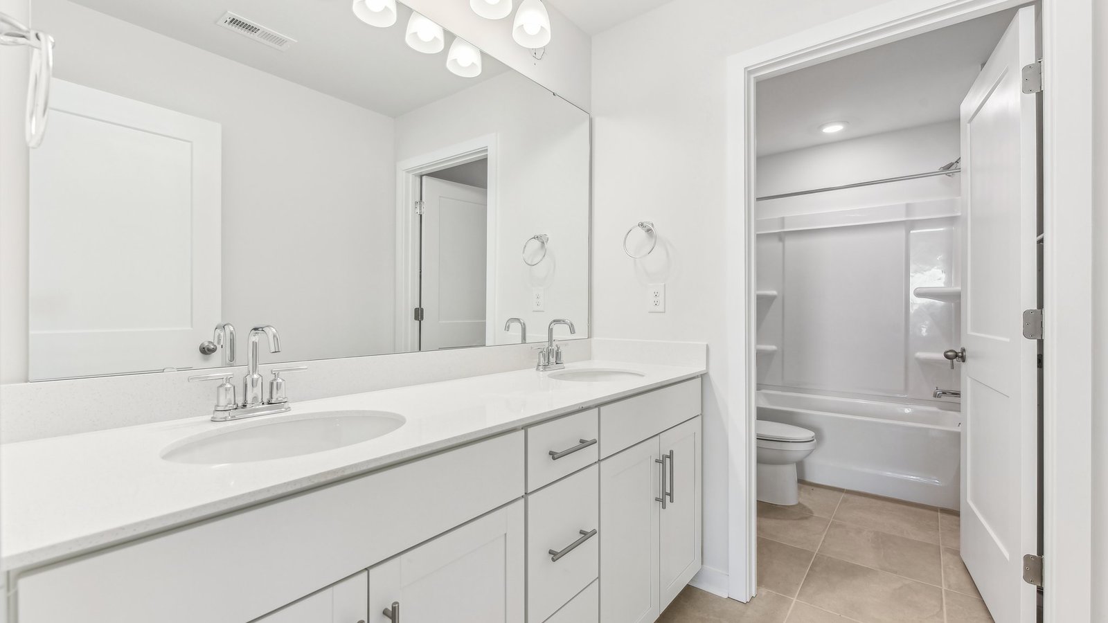 bathroom with double sinks and separate room for toilet and bathtub and shower combination