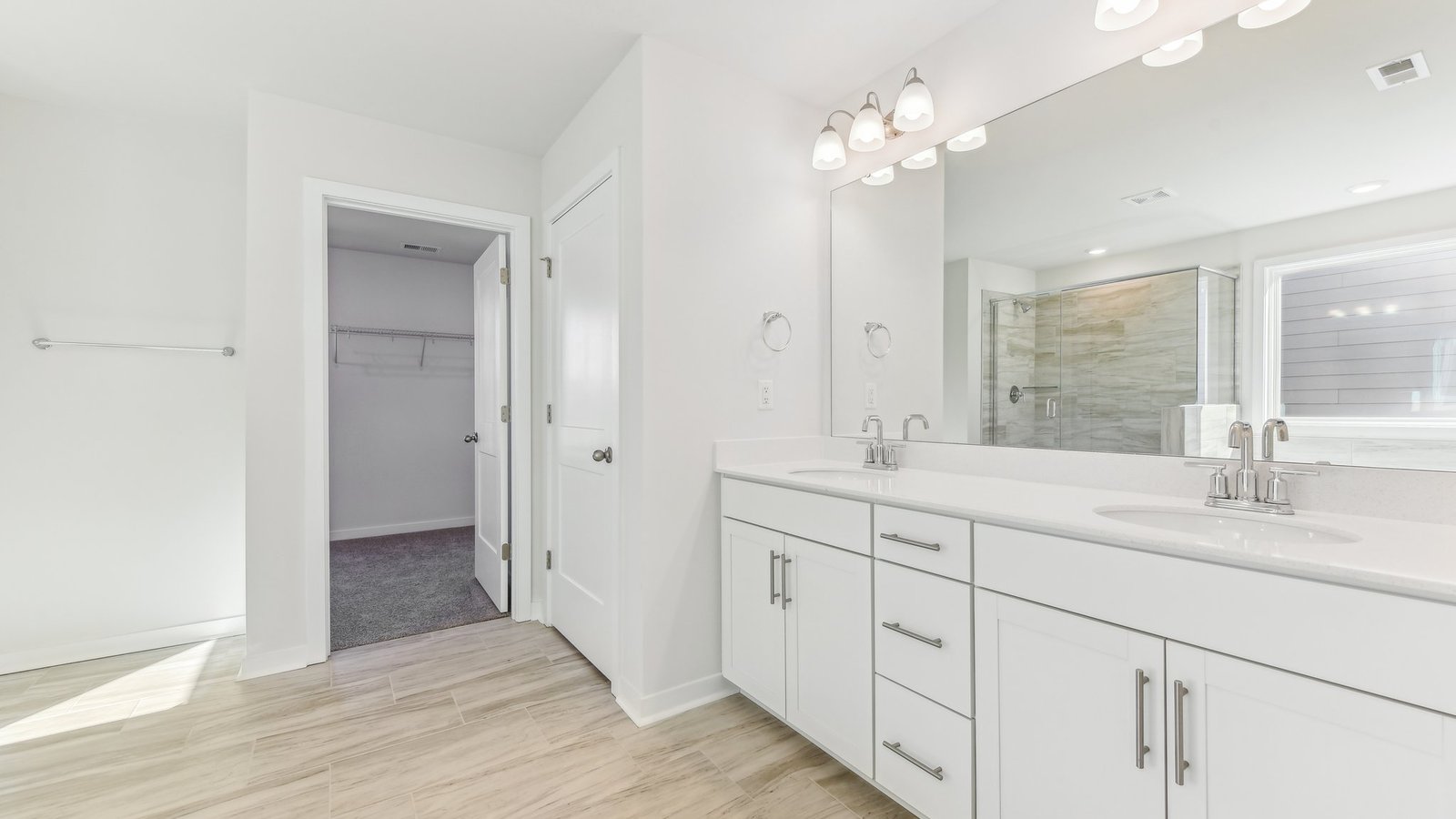 primary bathroom with dual vanity, bathtub and glass door shower