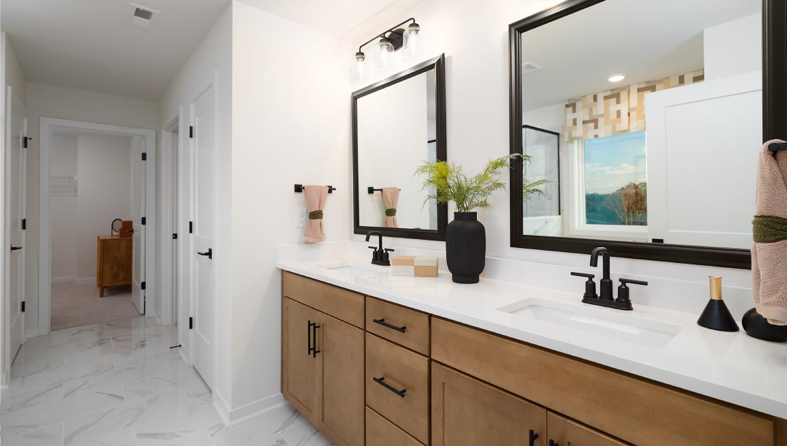 Primary bathroom with brown cabinets and large glass shower