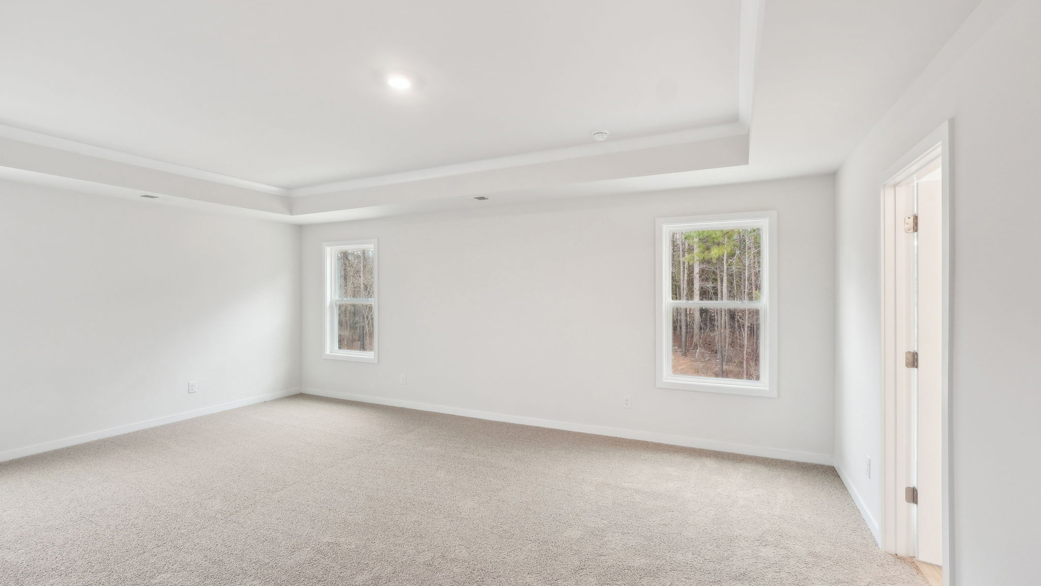 Primary carpeted bedroom with windows