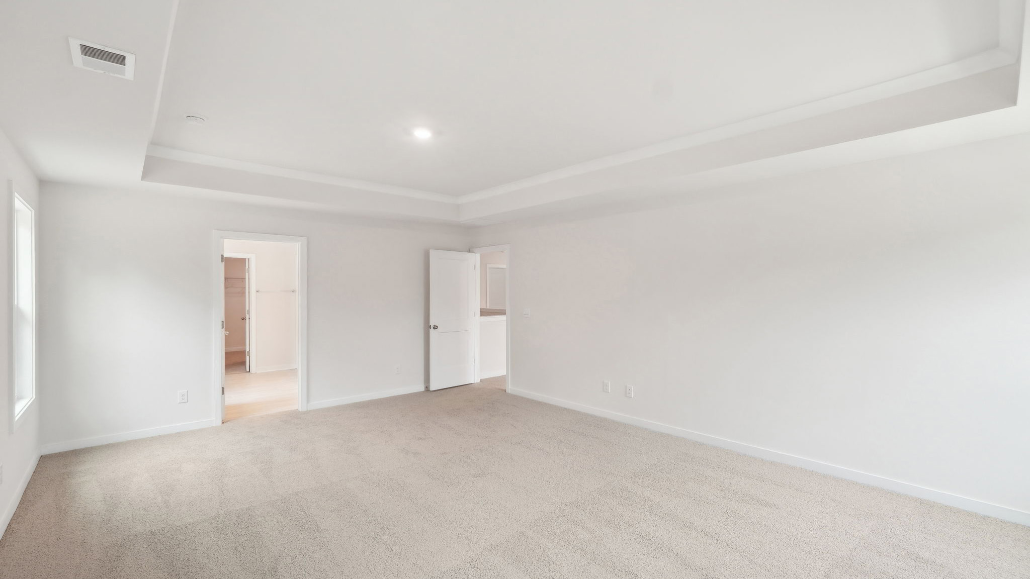 Primary carpeted bedroom with windows