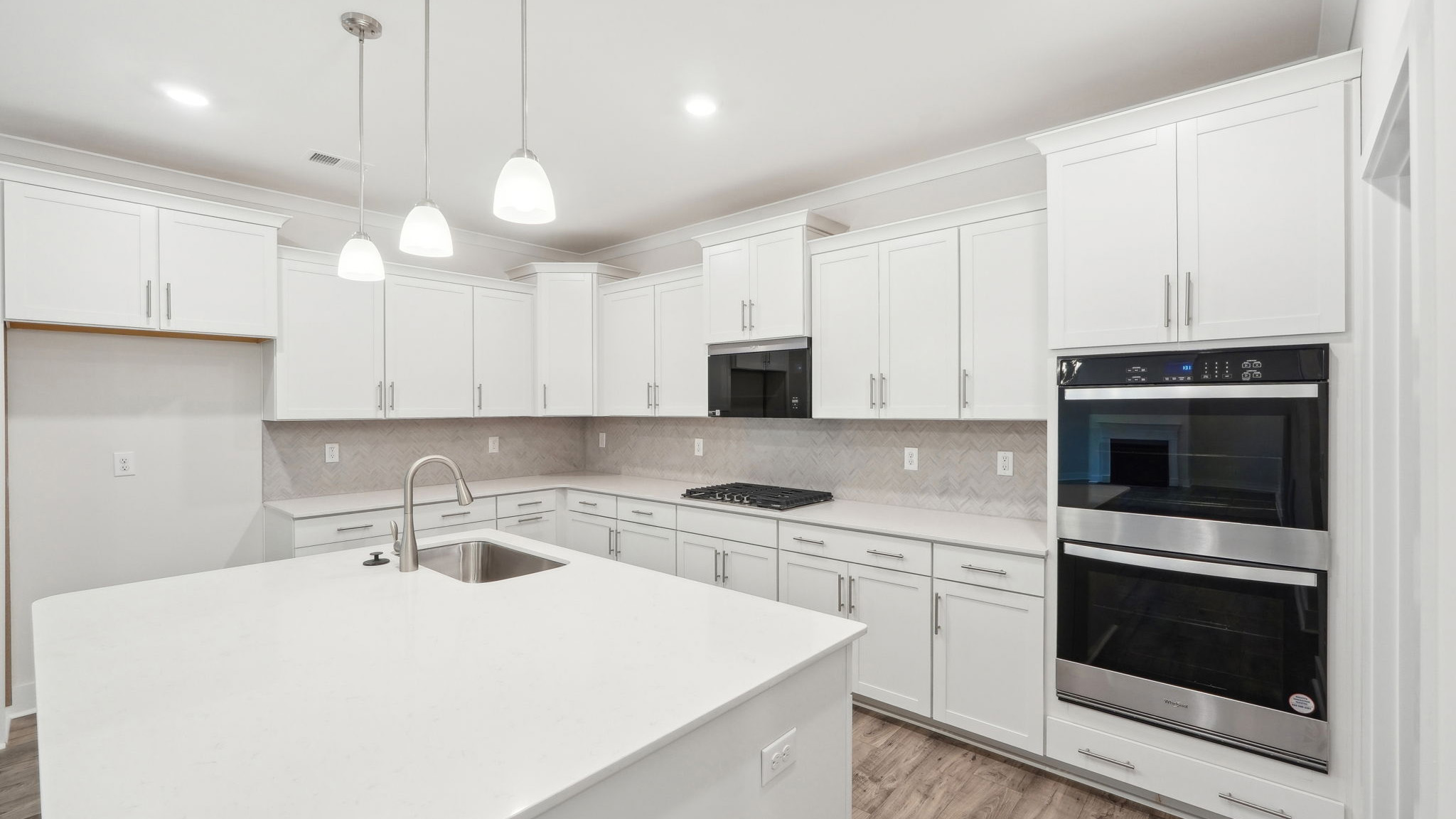 Kitchen and island with white cabinets and stainless steel appliances