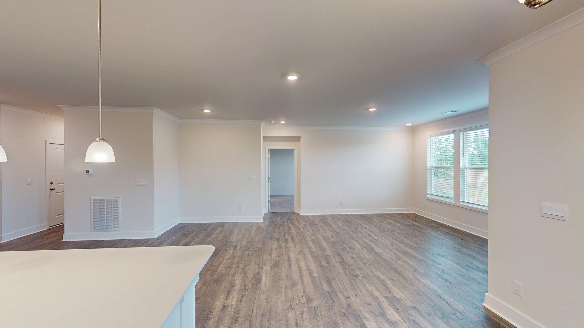 Living room with three large windows, beside dining area