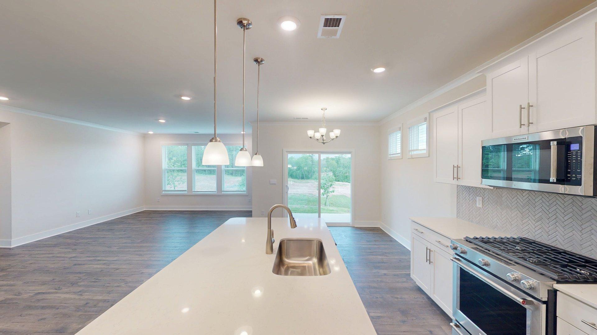 Kitchen and island with grey cabinets, white countertops, and stainless steel appliances