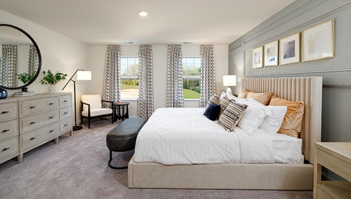 Fergus Crossing Penwell Model primary bedroom with carpet and two large windows