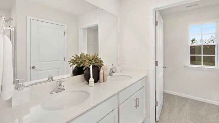 Primary bathroom with double sinks, white counters and cabinets, glass door shower