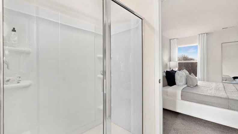 Primary bathroom with double sinks, white counters and cabinets, glass door shower