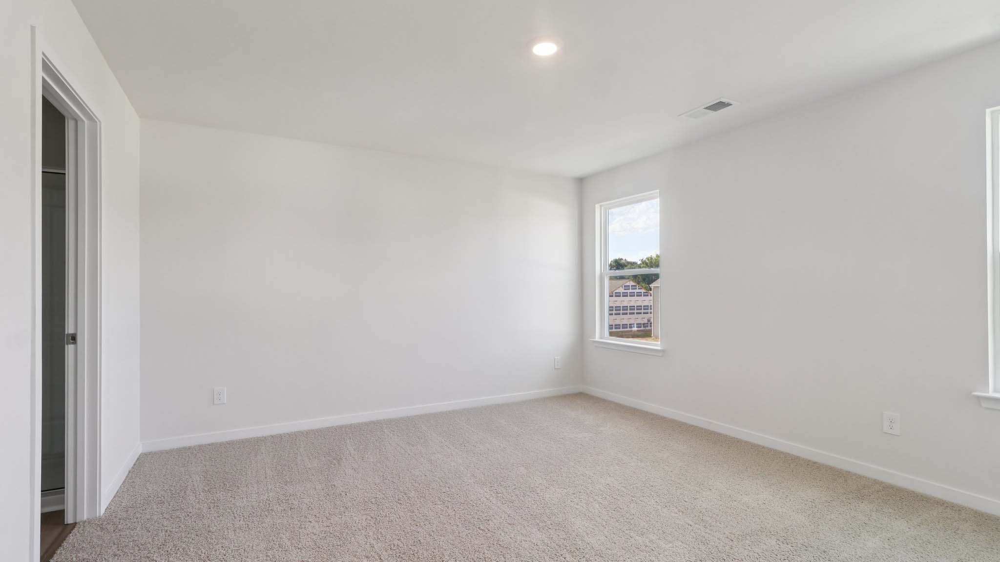 Primary carpeted bedroom with windows