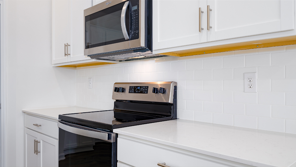 Kitchen and island with white cabinets, quartz counters, wood floors and stainless steel appliances