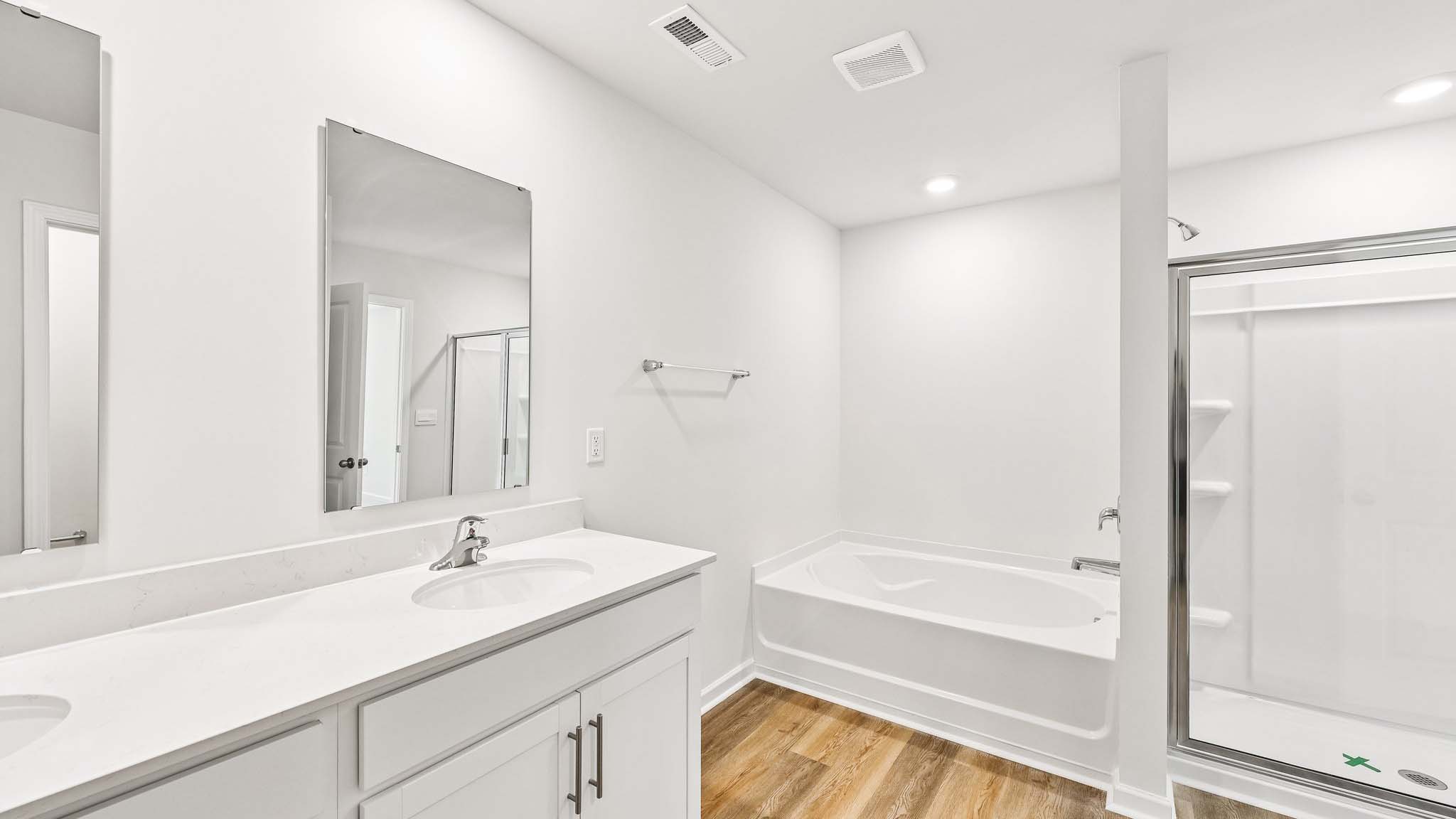 primary bathroom with dual vanity and walk in shower and soaking tub