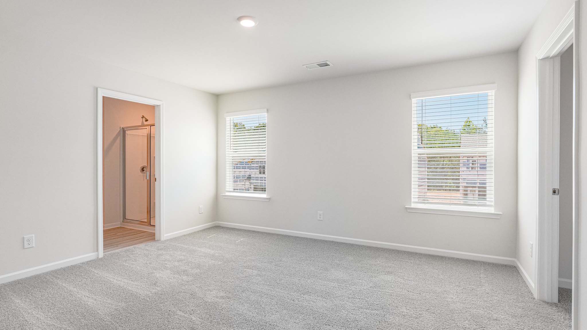 primary carpeted bedroom with windows