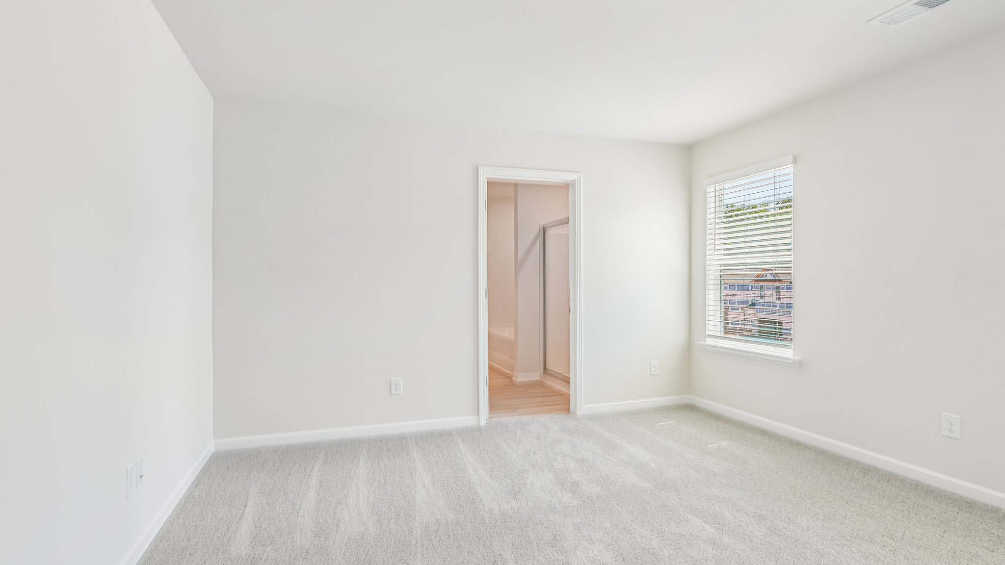 primary carpeted bedroom with windows