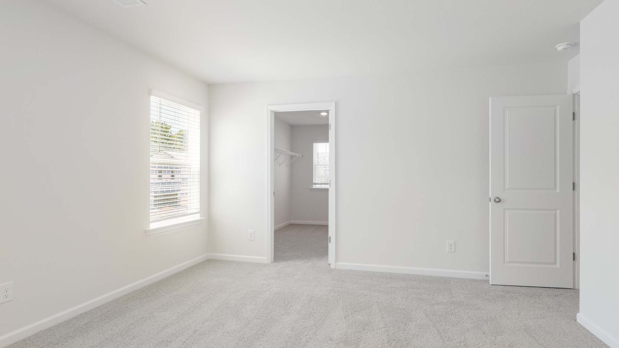 primary carpeted bedroom with windows