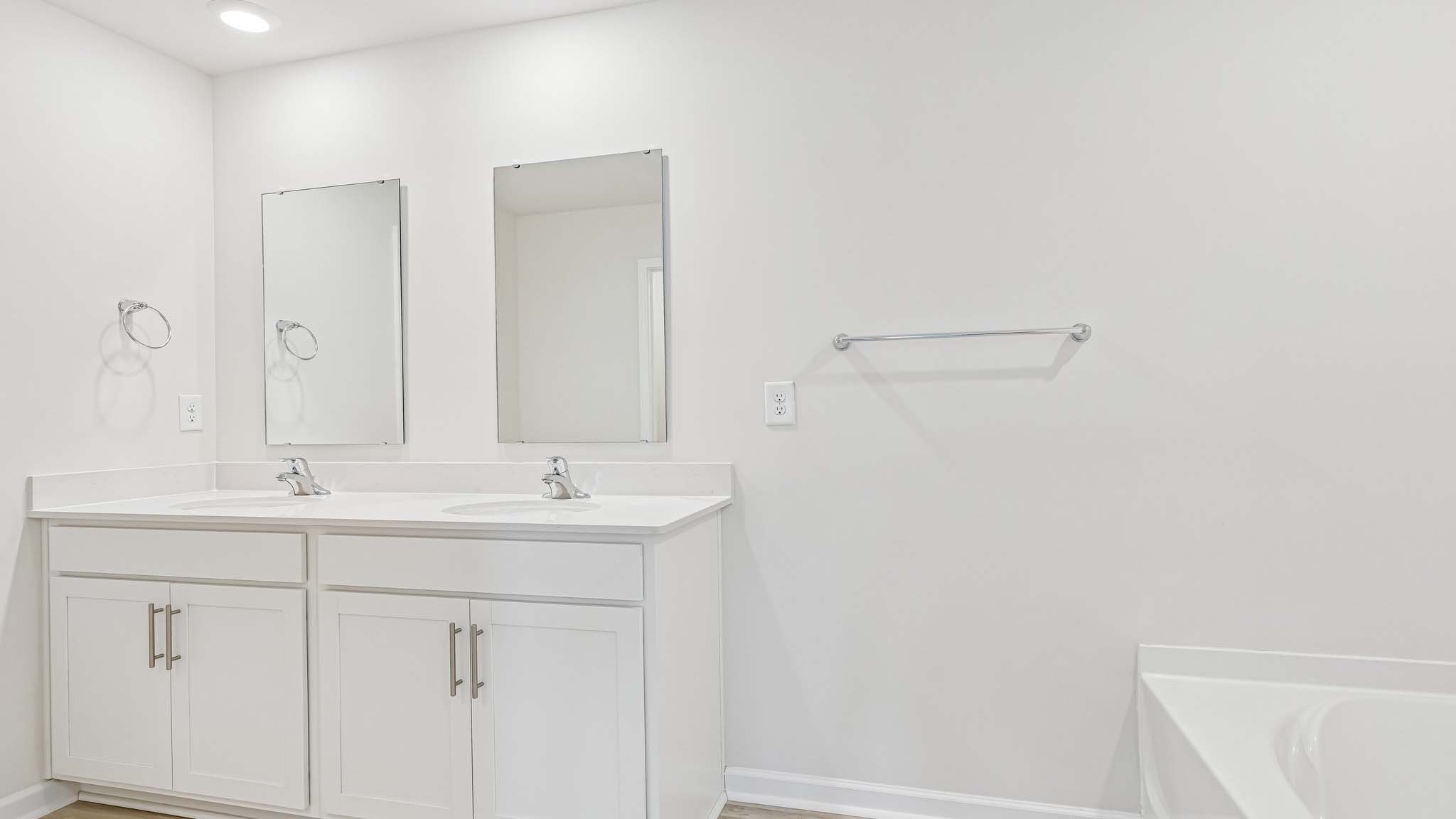 primary bathroom with dual vanity and walk in shower and soaking tub