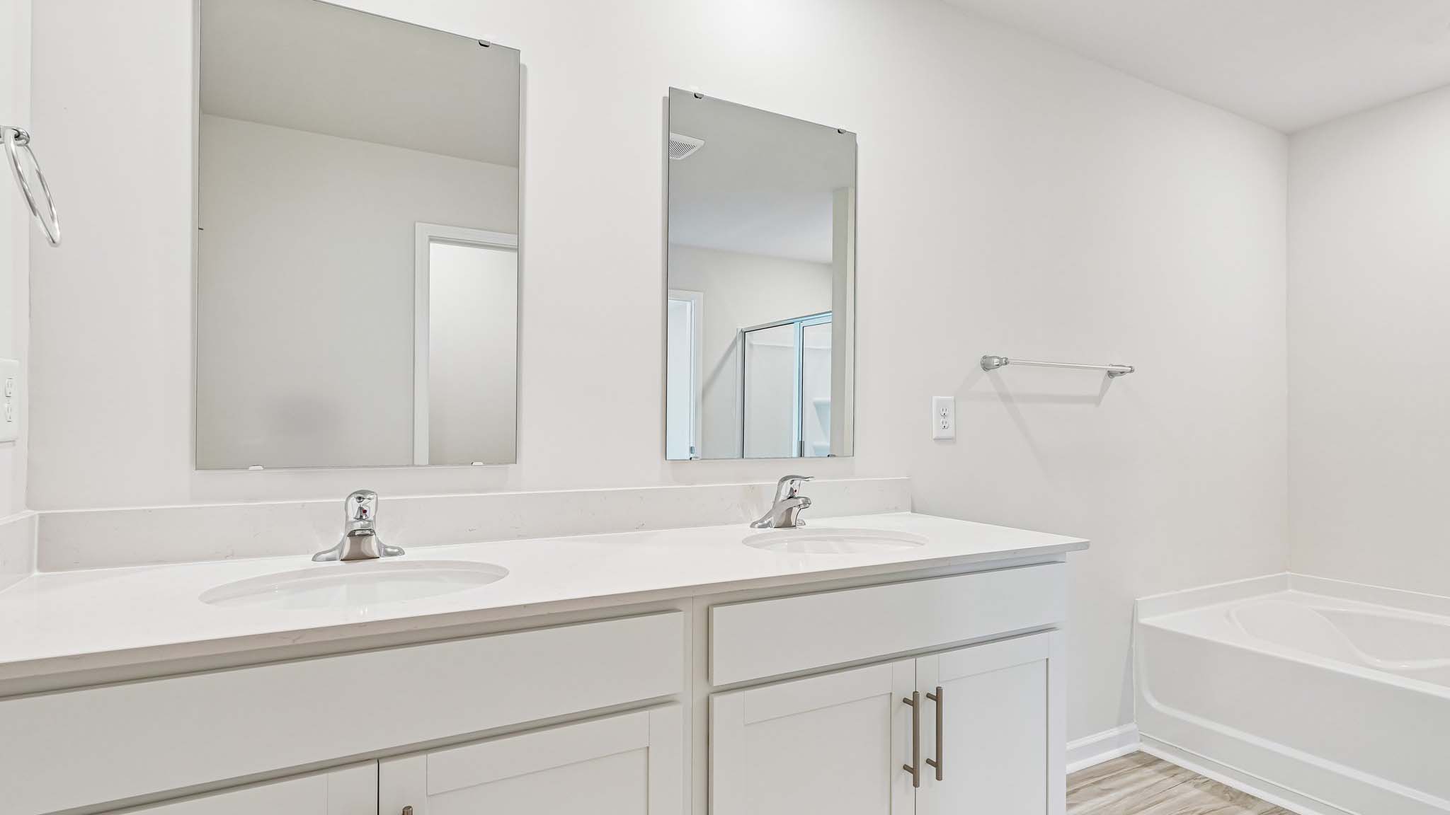 primary bathroom with dual vanity and walk in shower and soaking tub