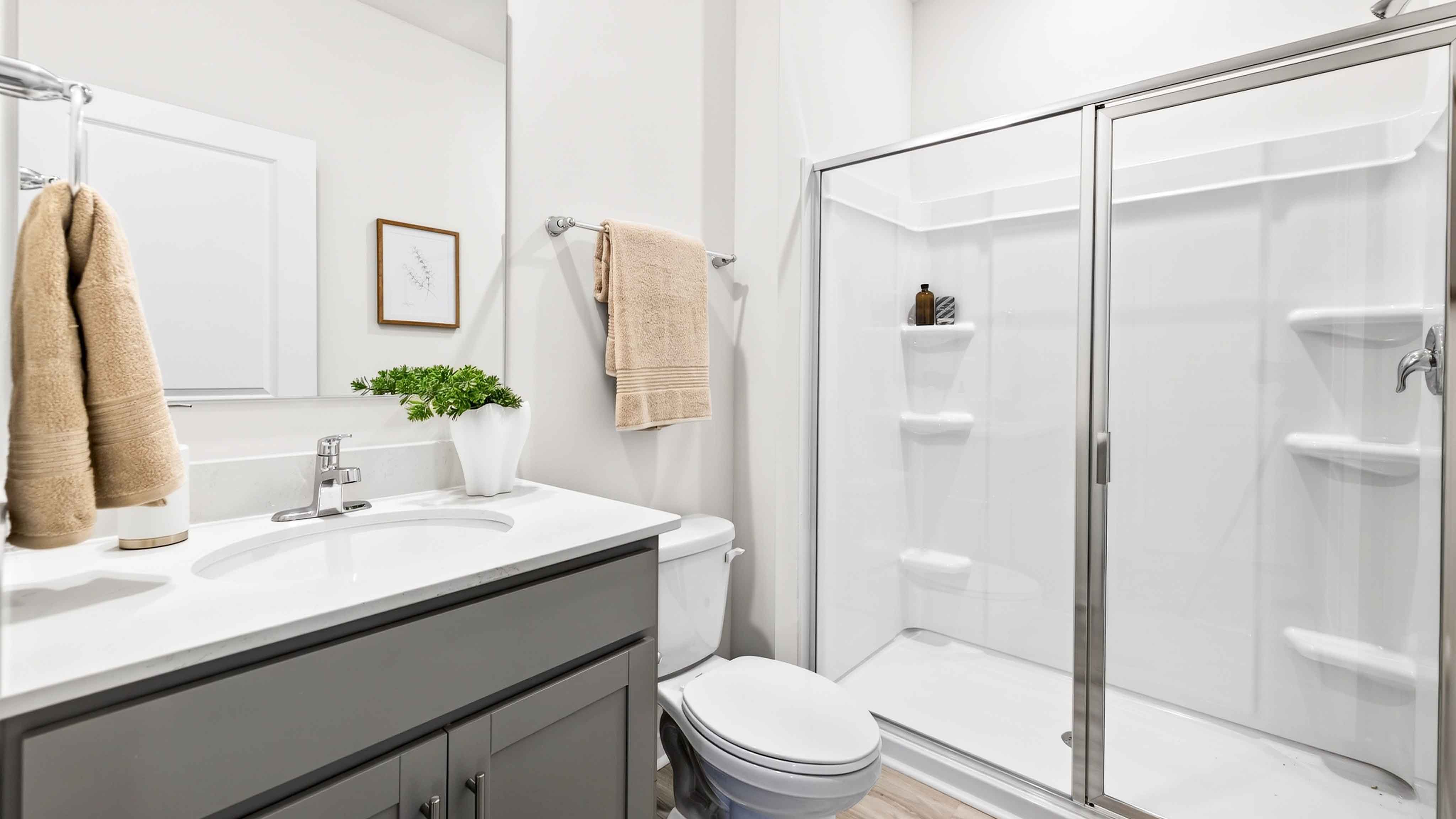 Bathroom with standing shower, white counter and cabinets